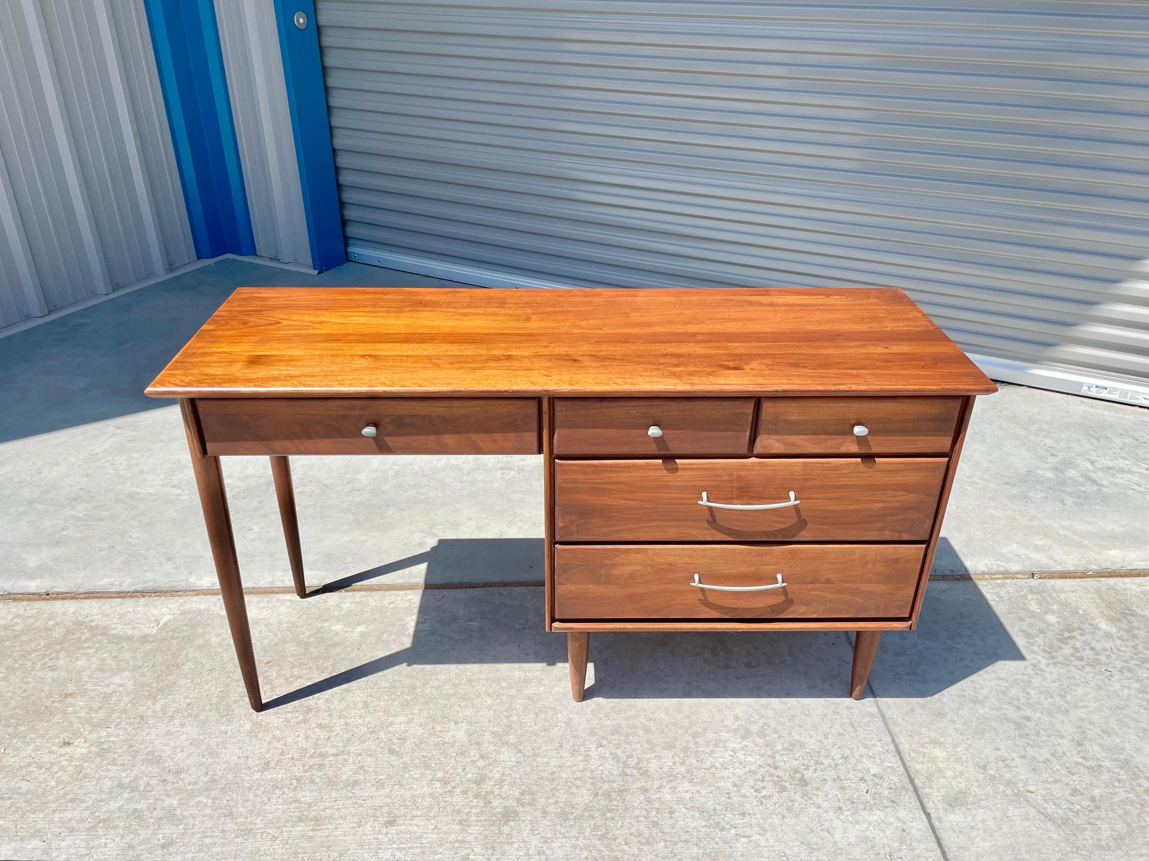 Mid-century walnut desk designed and manufactured by ACE-Hi in the United States circa 1960s. This beautiful writing desk features a walnut frame with five drawers giving you plenty of storage space. The drawers also feature metal handles making it