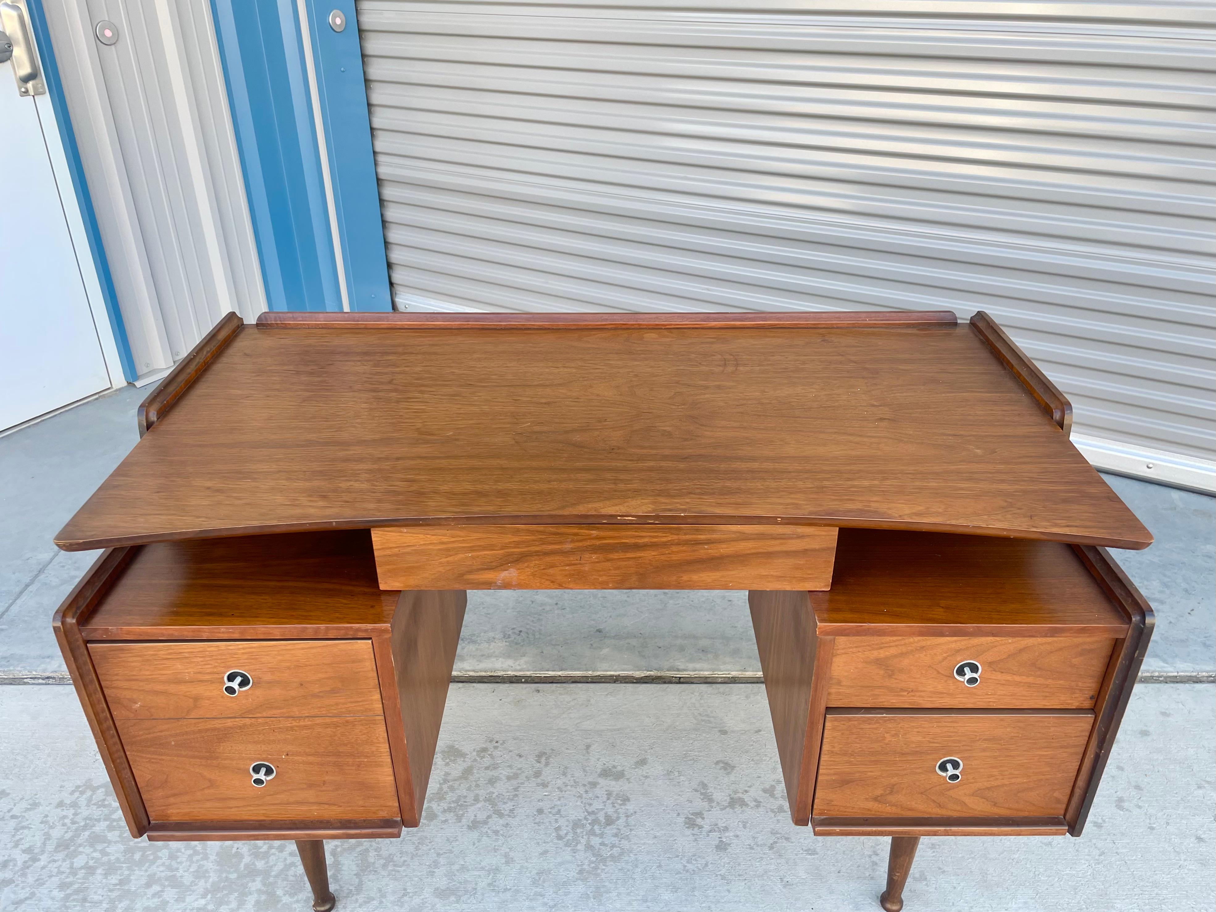 Mid-century walnut desk designed and manufactured by Hooker in the United States circa 1960s. This stunning desk features a walnut frame. The desk also comes with two pull-out drawers and one filing cabinet, giving you plenty of storage space for
