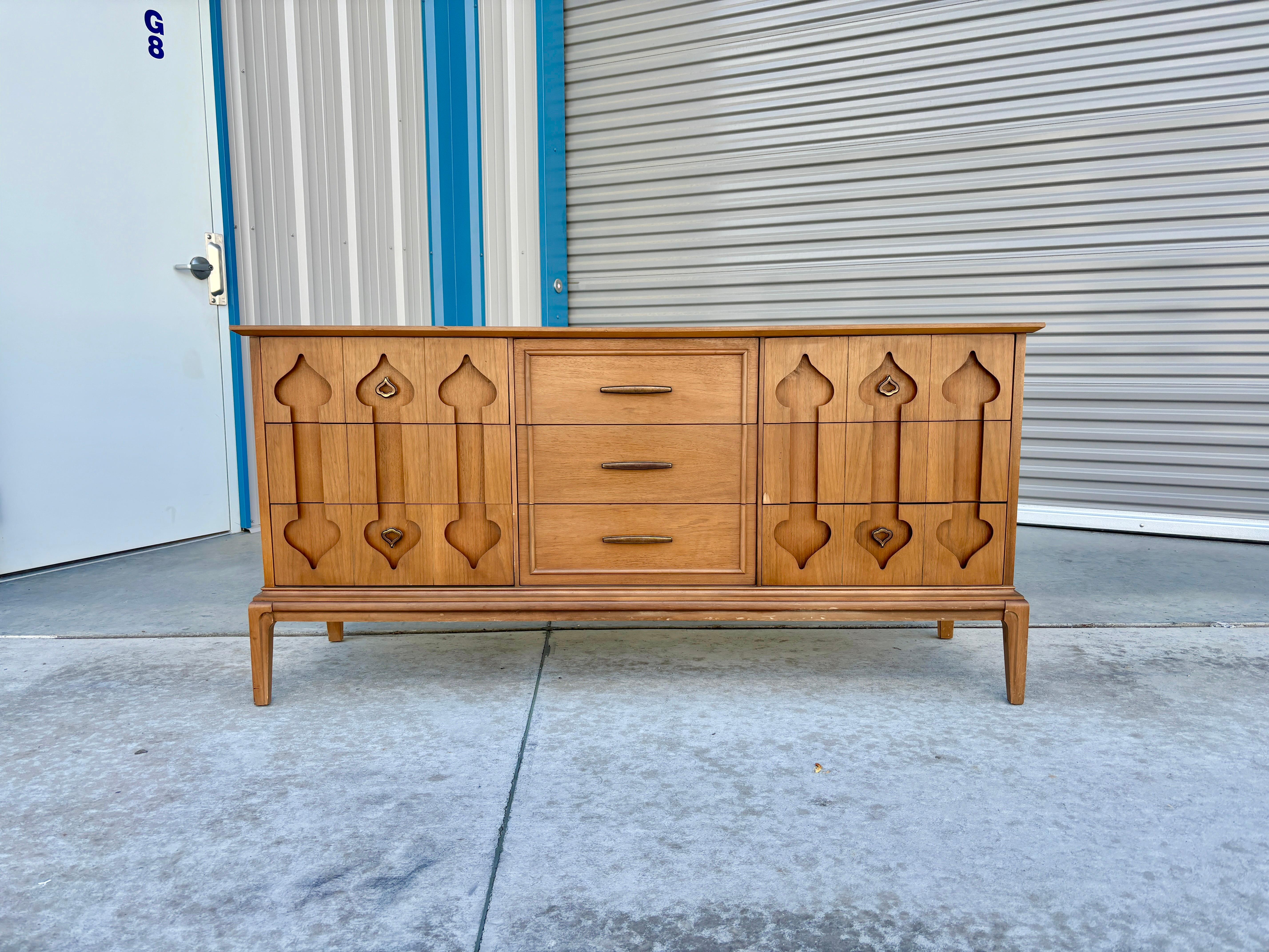 This mid-century walnut dresser was designed and manufactured by Bakers in the United States in the 1960s. This fantastic dresser features a walnut frame that exudes timeless elegance. The nine pull-out drawers offer ample storage space, with the