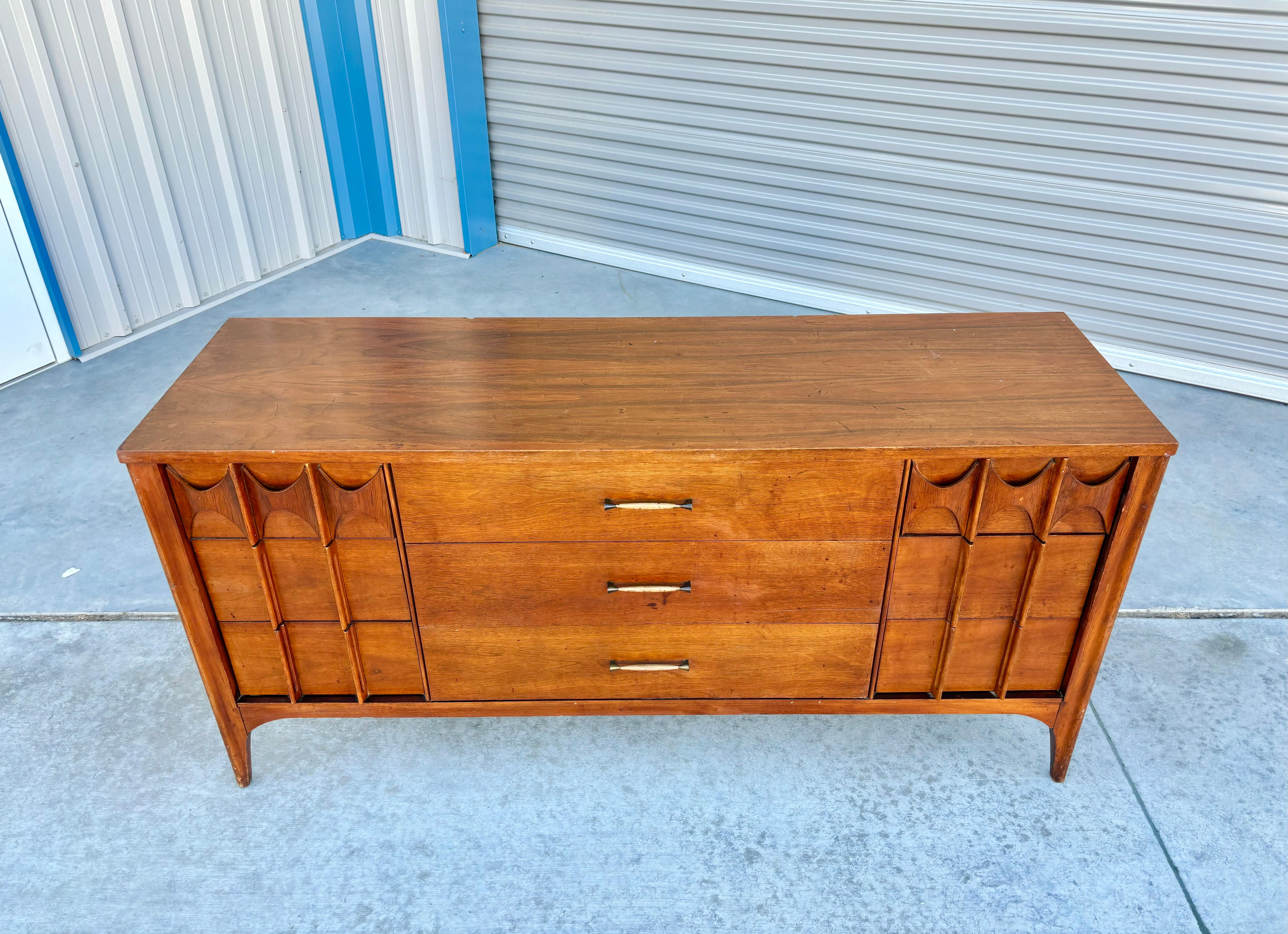 Mid century walnut dresser designed and manufactured by Kent Coffey in the United States circa 1960s.This elegant dresser boasts a sturdy walnut frame that exudes a timeless charm and features stunningly sculpted handles that add an element of