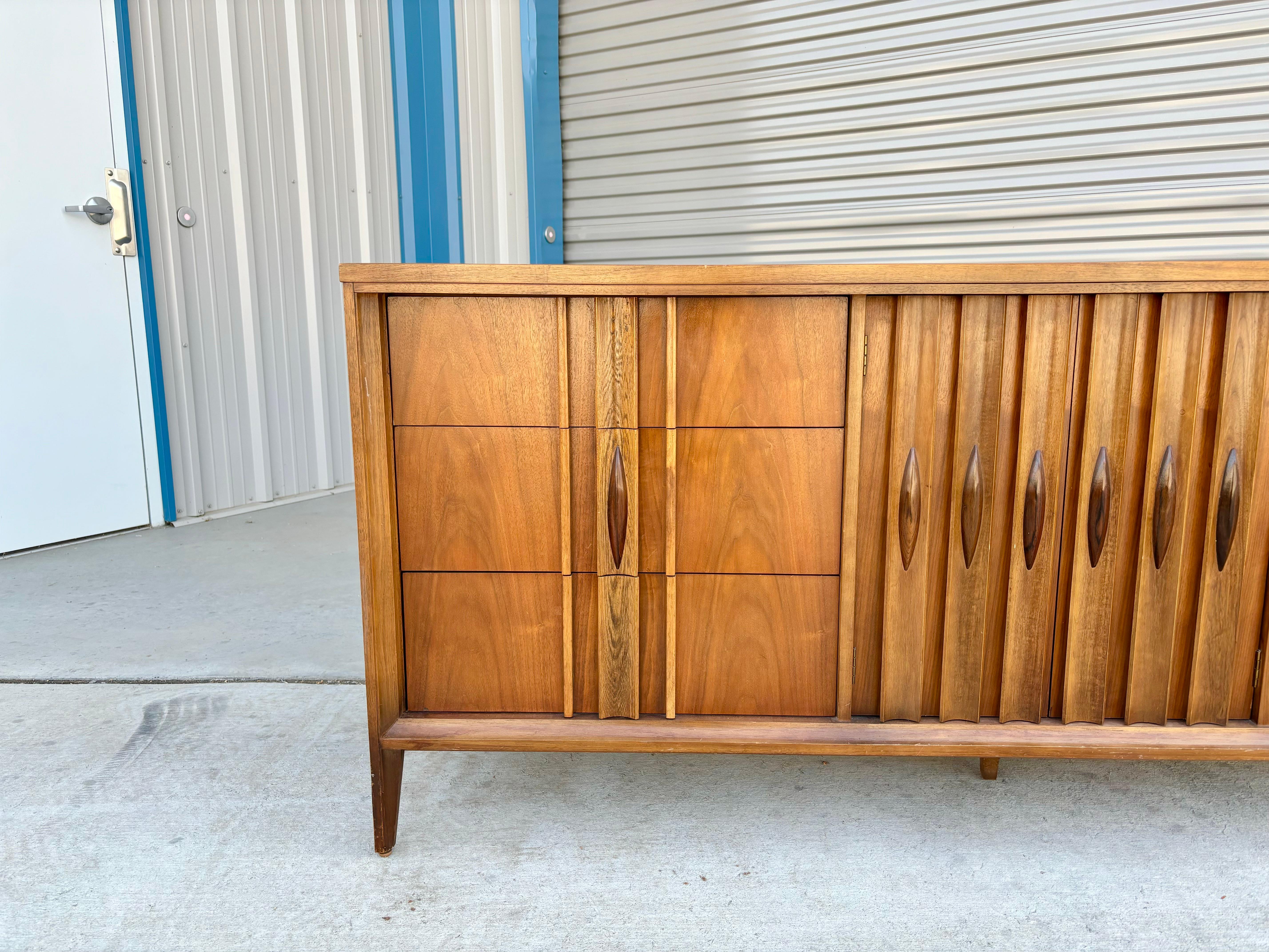 Mid-century walnut sculpted walnut dresser designed by Thomasville in the United States circa 1960s. This stunning dresser features a walnut frame with a unique sculptured rosewood handle. The dresser also comes with nine pull-out drawers, giving