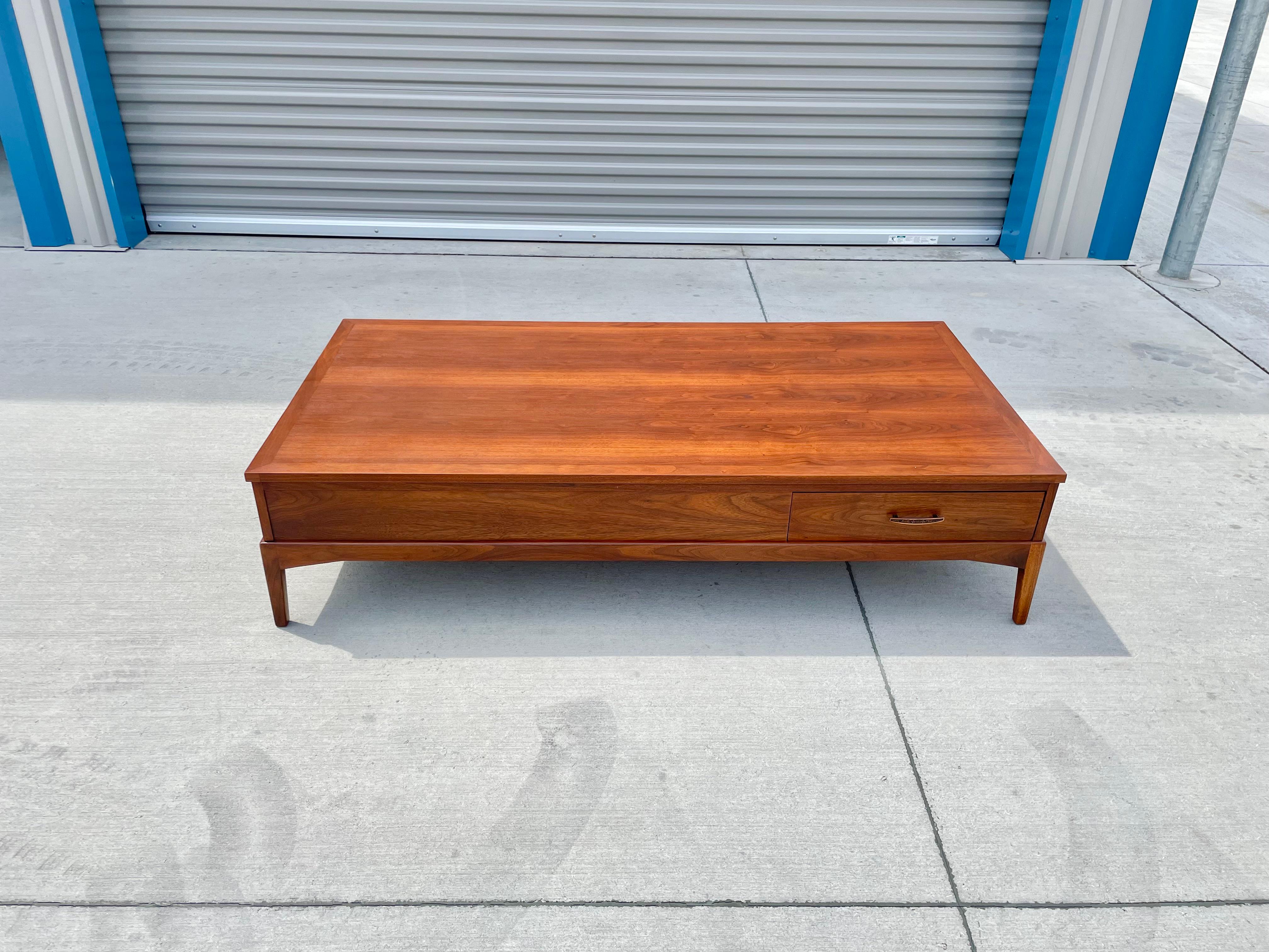 Mid-century walnut coffee table designed and manufactured by Lane in the United States circa 1960s. This fantastic coffee table features a walnut frame with one pull-out drawer that pulls out both ways, the perfect addition for your home or office.