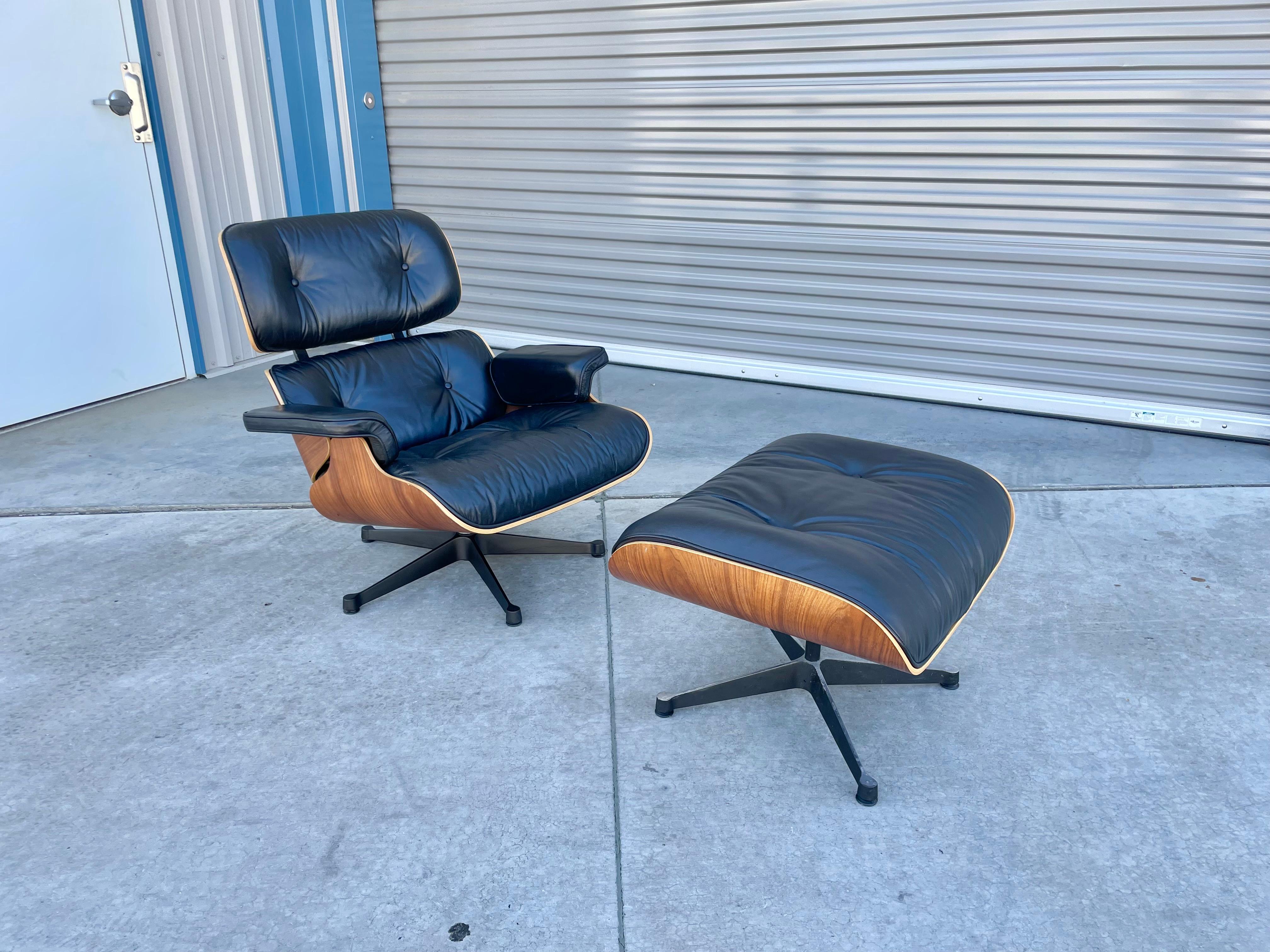 Sessel und Ottomane aus der Mitte des Jahrhunderts, entworfen von Charles Eames und hergestellt von Vitra um 1980. Dieses Set ist mit seiner schwarzen Lederpolsterung und dem einzigartigen Walnussschalenrahmen, der auf einem drehbaren Sockel sitzt