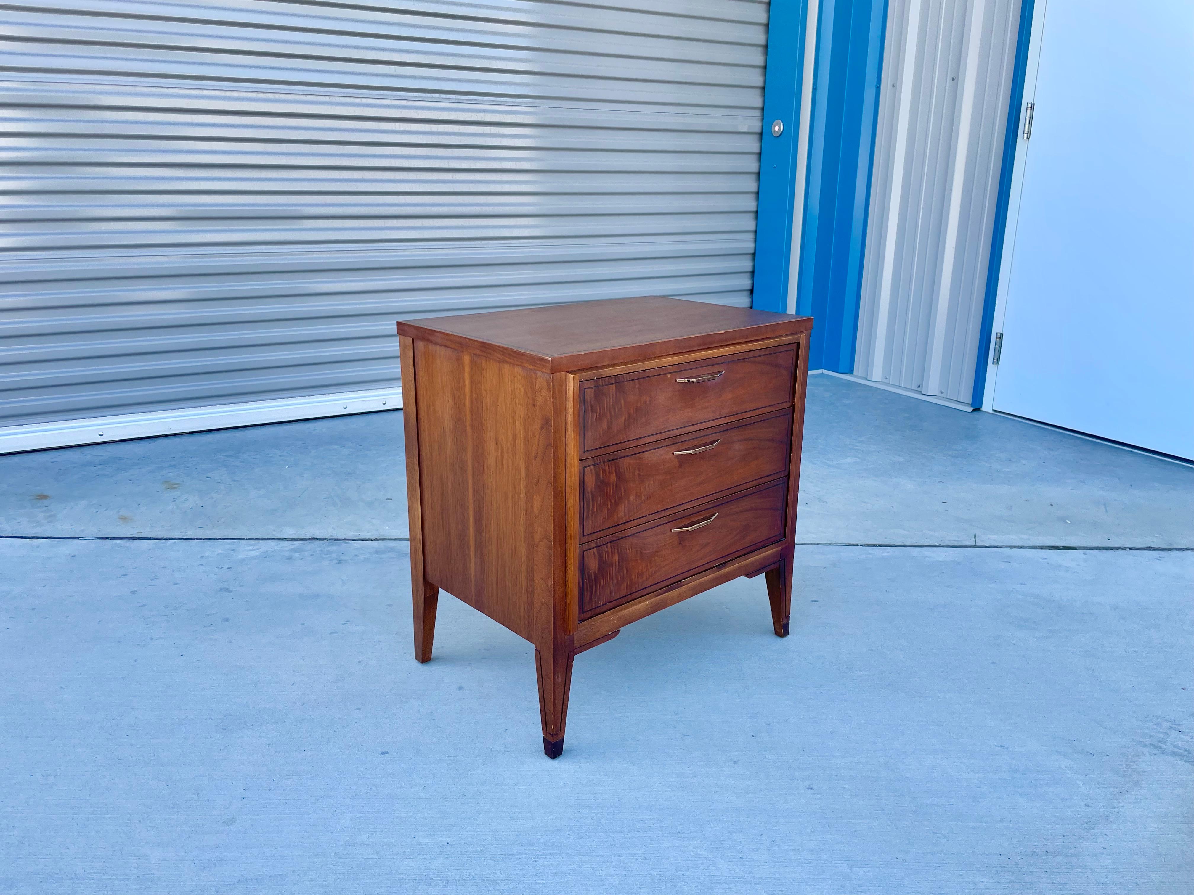 Mid-century walnut nightstand designed and manufactured by Kent Coffey in the United States circa 1960s. This beautiful nightstand features a walnut frame with three pull-out drawers giving you plenty of room for all your household needs.