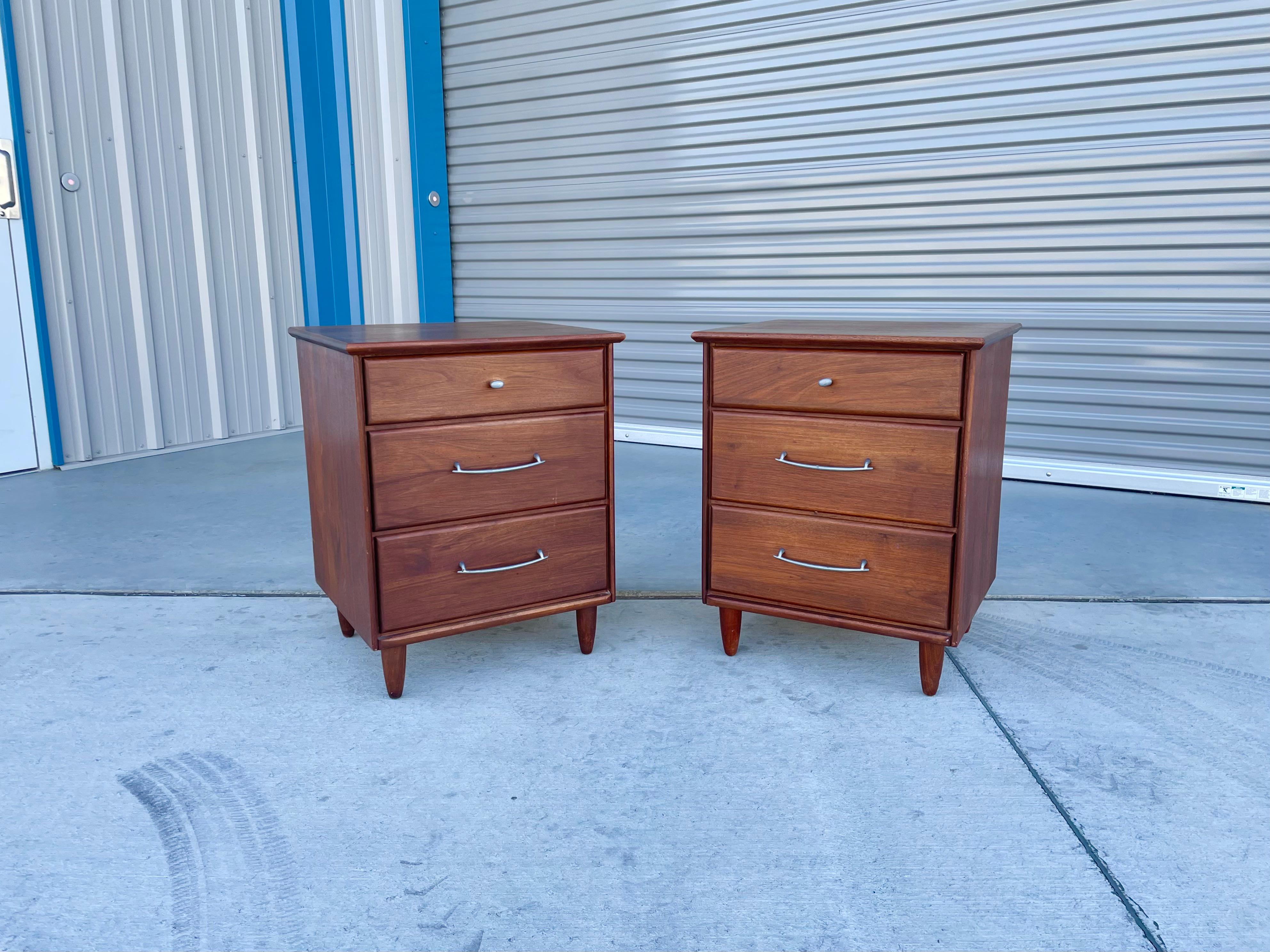 These Mid-century walnut nightstands designed and manufactured by Ace-Hi in the United States circa 1960s. This stunning pair of nightstands features a walnut frame with three pull-out drawers on each nightstand, giving you plenty of storage space.
