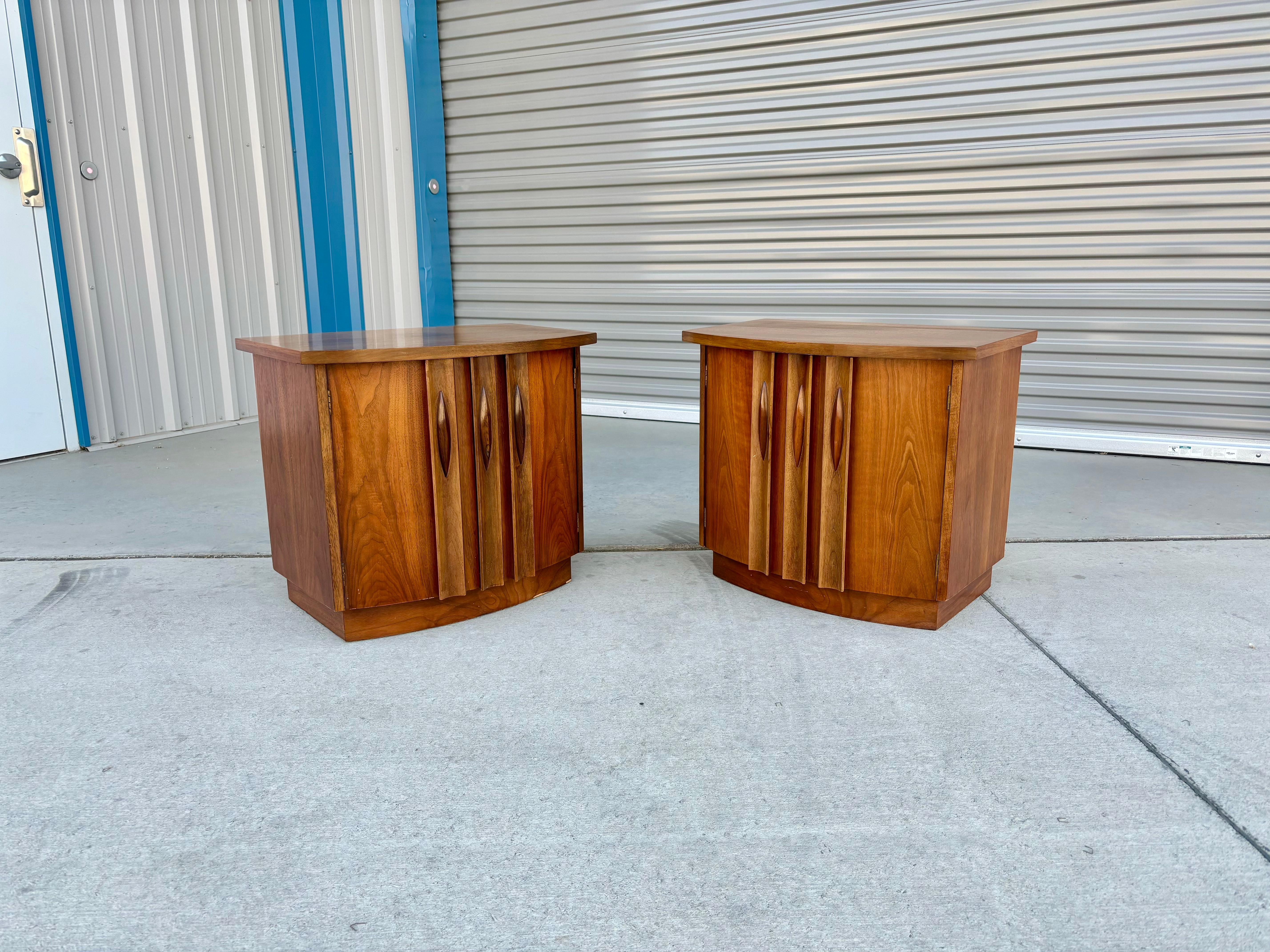 Mid-century walnut nightstands designed and manufactured by Thomasville in the United States circa 1960s. These beautiful nightstands feature a walnut frame with a unique sculptured handle, making it easy to pull. The nightstands also feature a