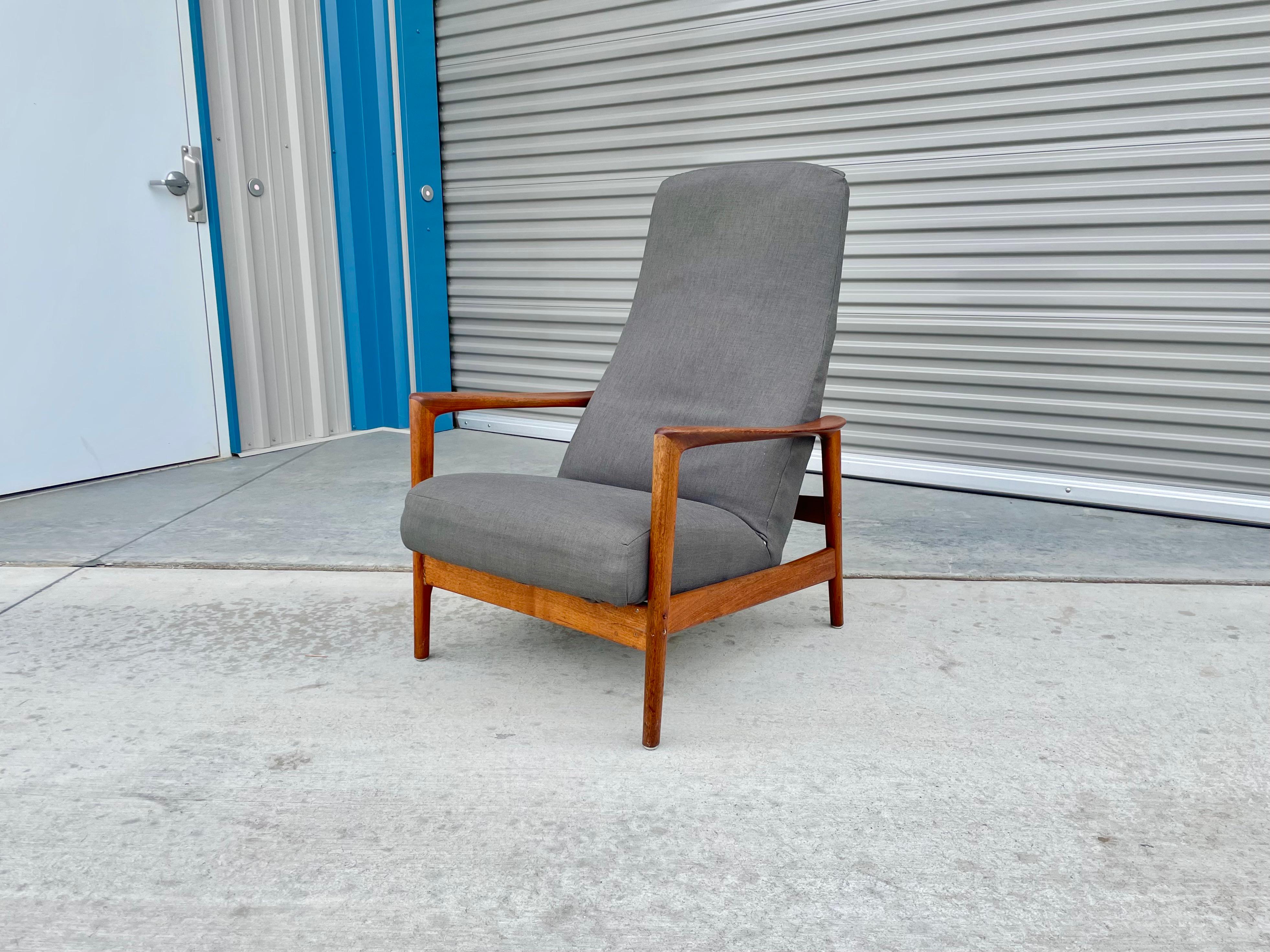 This mid-century walnut recliner was designed by Folke Ohlsson and manufactured by Dux in Sweden circa 1960s. This fantastic recliner features a walnut frame with gray upholstery. The chair also features an adjustable tilt mechanism that can lock