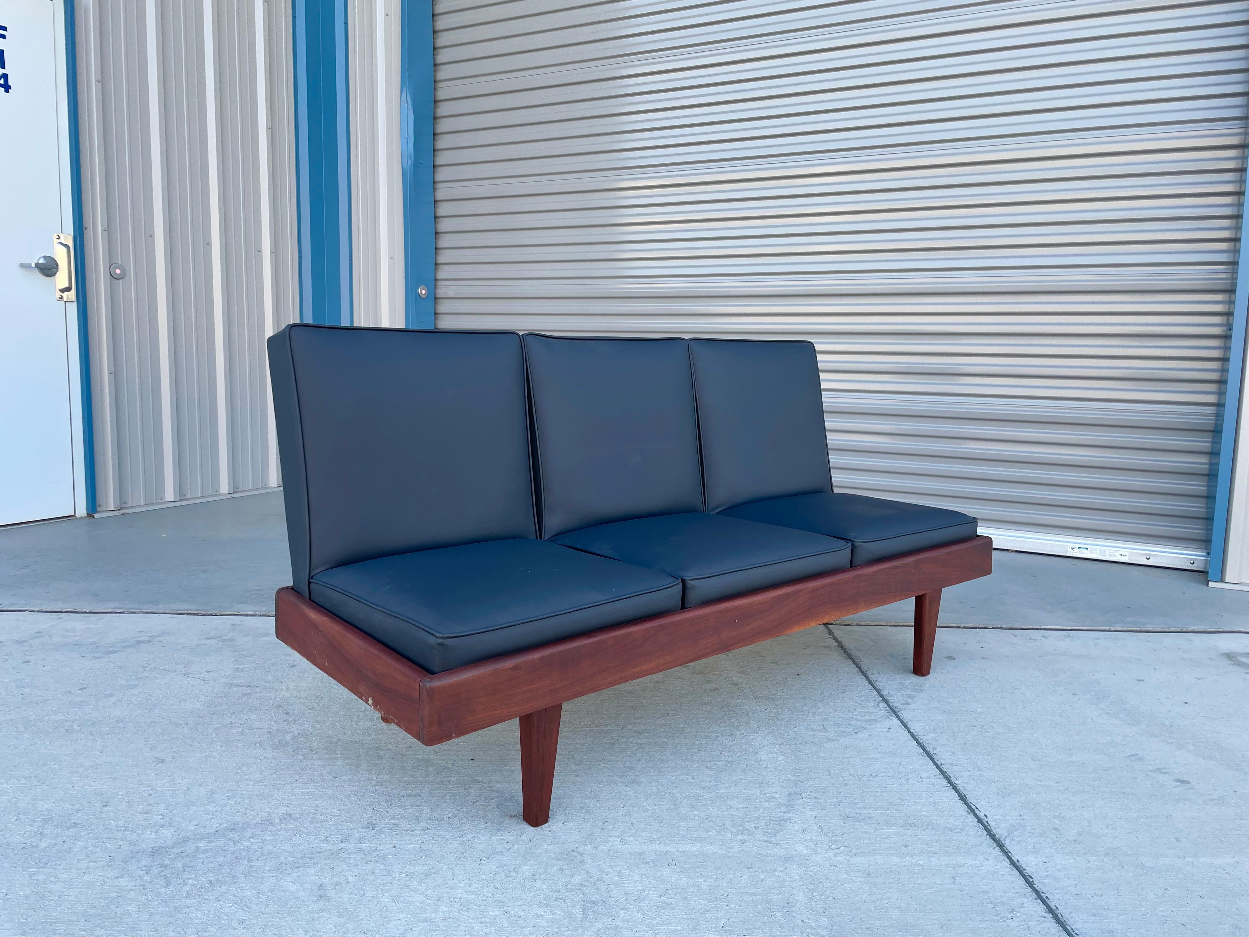 Sofa aus der Mitte des Jahrhunderts aus Nussbaum und Vinyl, entworfen und hergestellt in den Vereinigten Staaten um 1960, mit einem schönen schwarzen Vinylbezug, der auf einem eleganten und stilvollen Nussbaumrahmen sitzt, der nicht nur gut