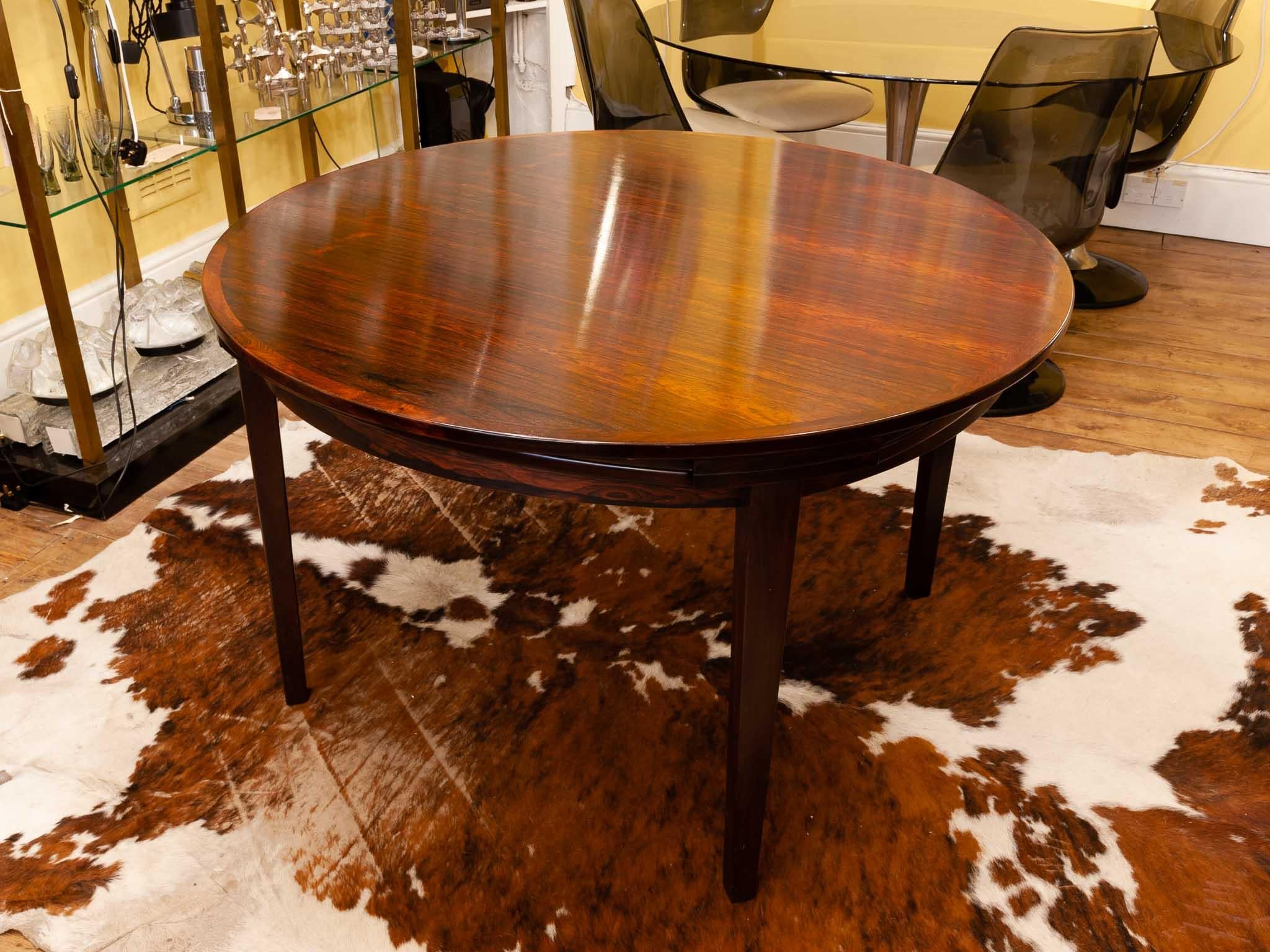 Danish Rosewood Flip-Flap Lotus dining table manufactured by Dyrlund in the 1960s. The table is their version with four legs with a wide diameter of 1.2m when not extended. The four 'flip-flap' extension leaves slide neatly underneath the table-top