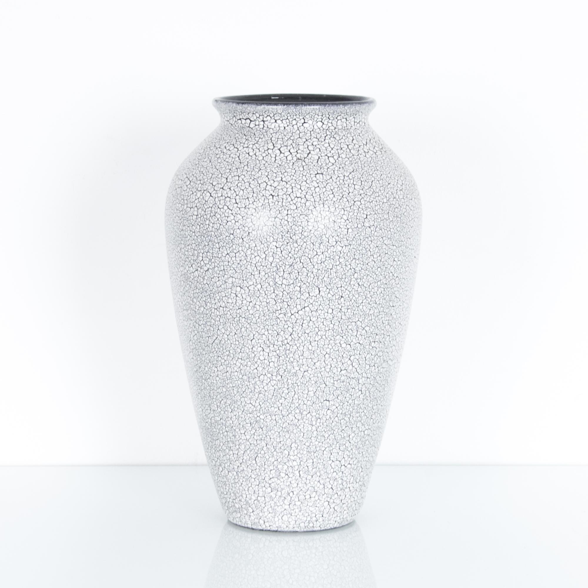 Striking and subtle, this black and white vase comes from Germany circa 1940, embellished with a minute texture, a crackled white glaze on a black under layer. These characteristic mid-20th century ceramics were produced in West Germany, featuring
