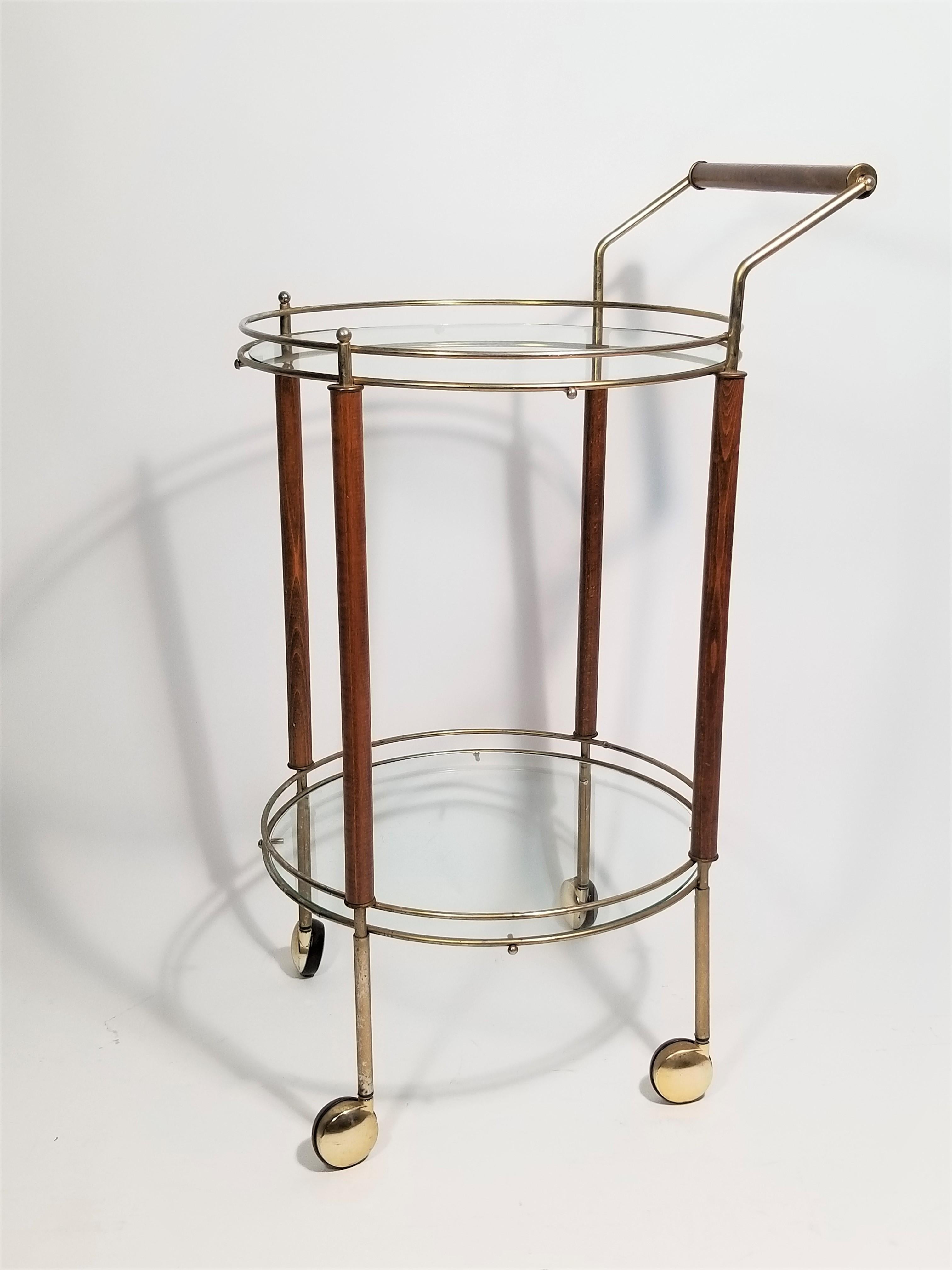 1960s, midcentury Italian round rolling bar cart. Two glass tiers. Walnut and brass frame. Walnut handle. Wheels roll easily. Nice compact size would make this ideal for smaller spaces.
Complimentary free delivery can be arranged in NYC and