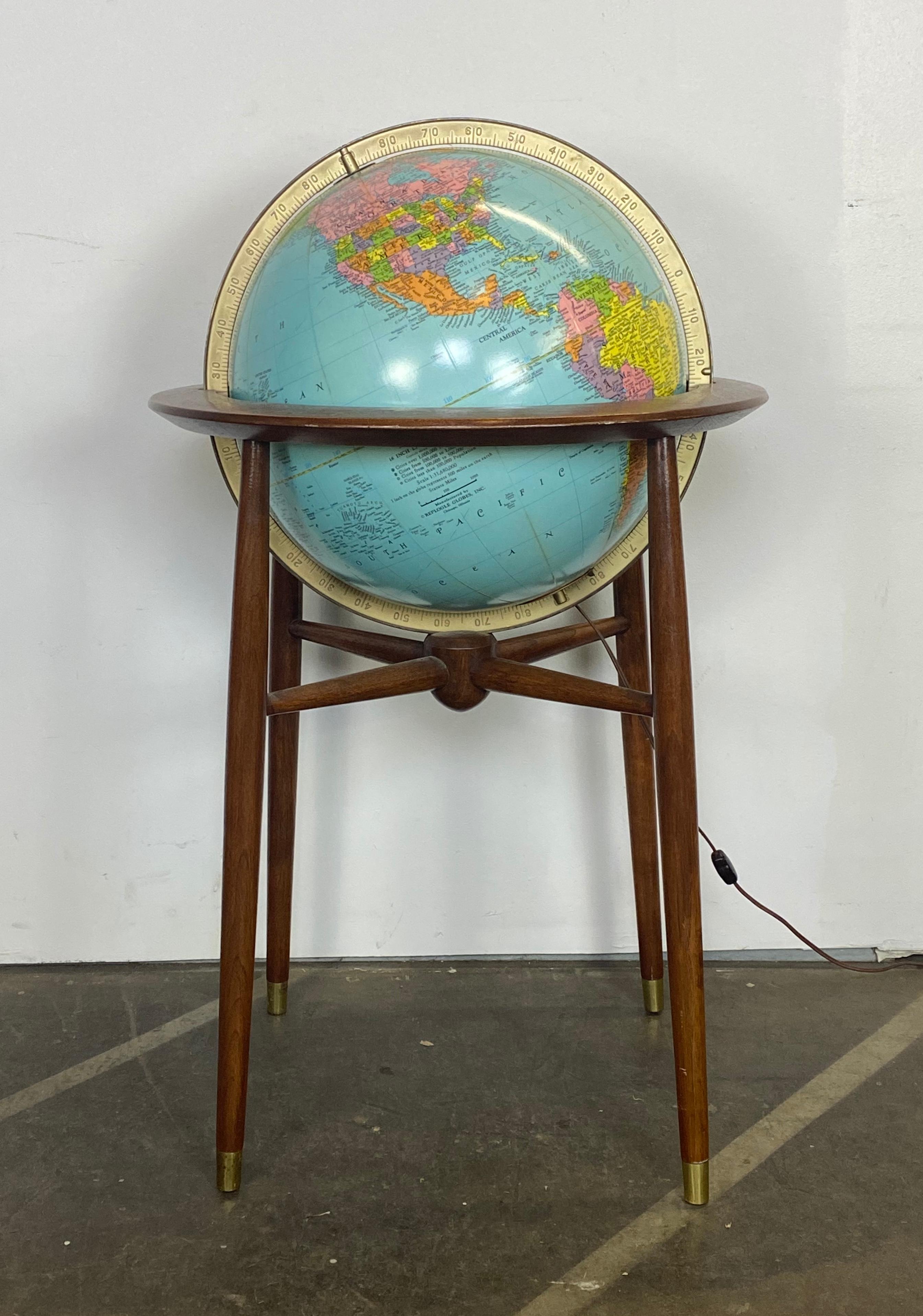 Amazing classic 1960s globe. Made by Replogle featuring bright and distinct colors. With illuminated feature and accommodates modern bulbs. Tested and working. Walnut frame in good condition with sculpted simple yet elegant form, including brass