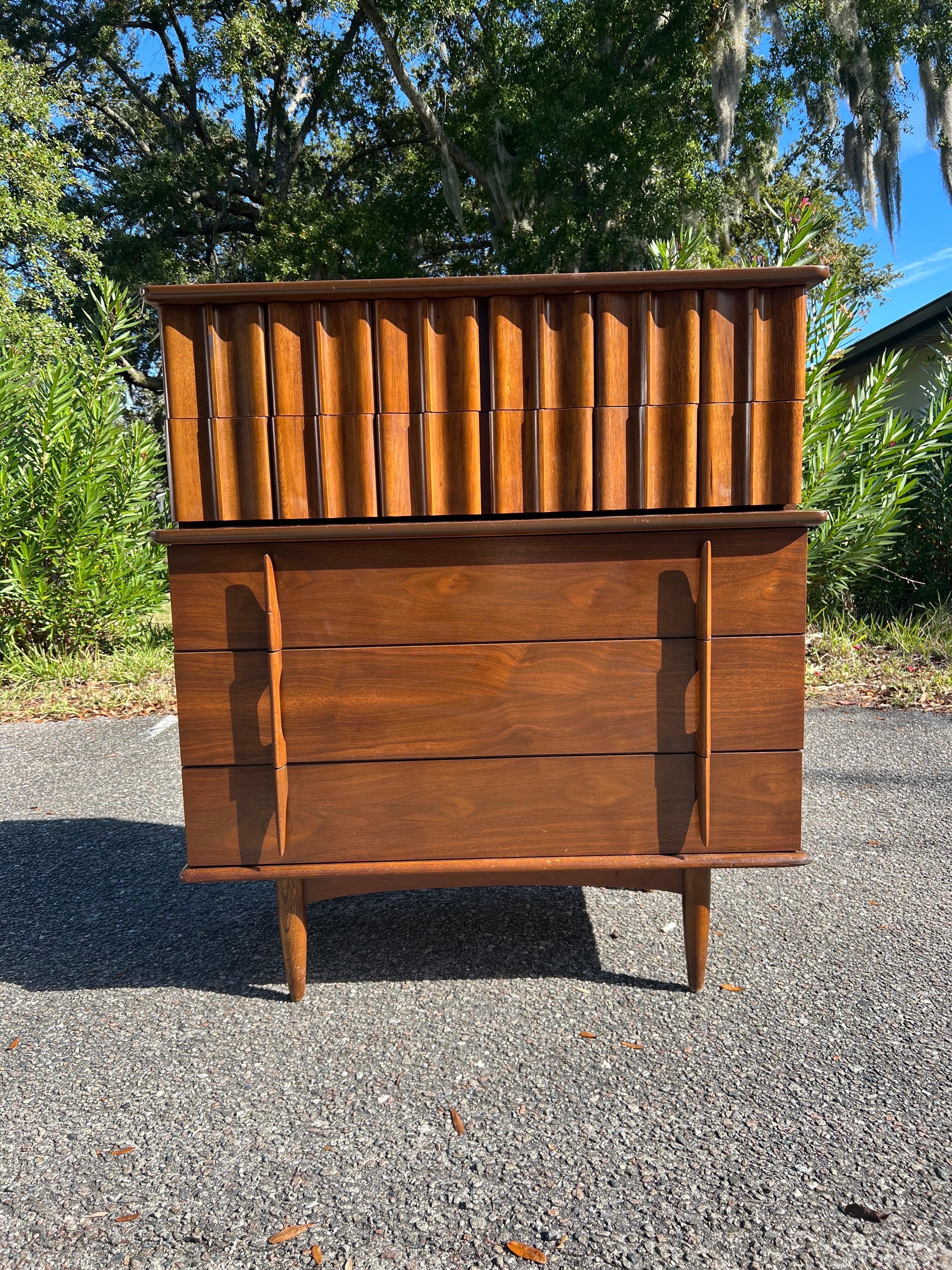 A remarkable midcentury highboy dresser by United in very good vintage condition. Exceptional construction and style, features a unique set of sculpted double drawers, constructed out of rich walnut, having five dove tailed spacious drawers two on