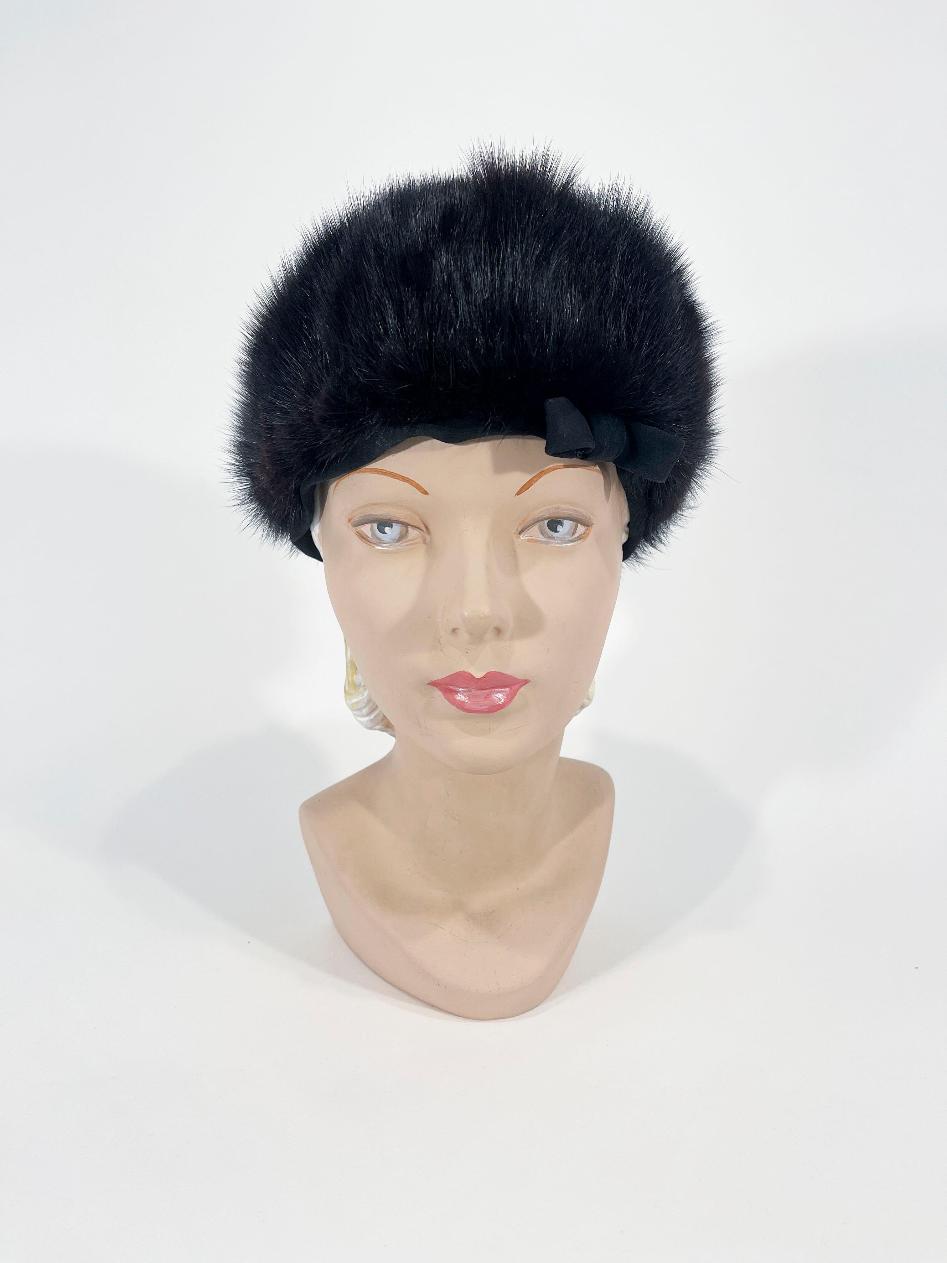 1960s extremely dark brown (almost black) mink hat is made of several strips of mink configured into a pinwheel-like pattern with a black bank finished bit a bow. The interior is lined with a heavy black taffeta.
