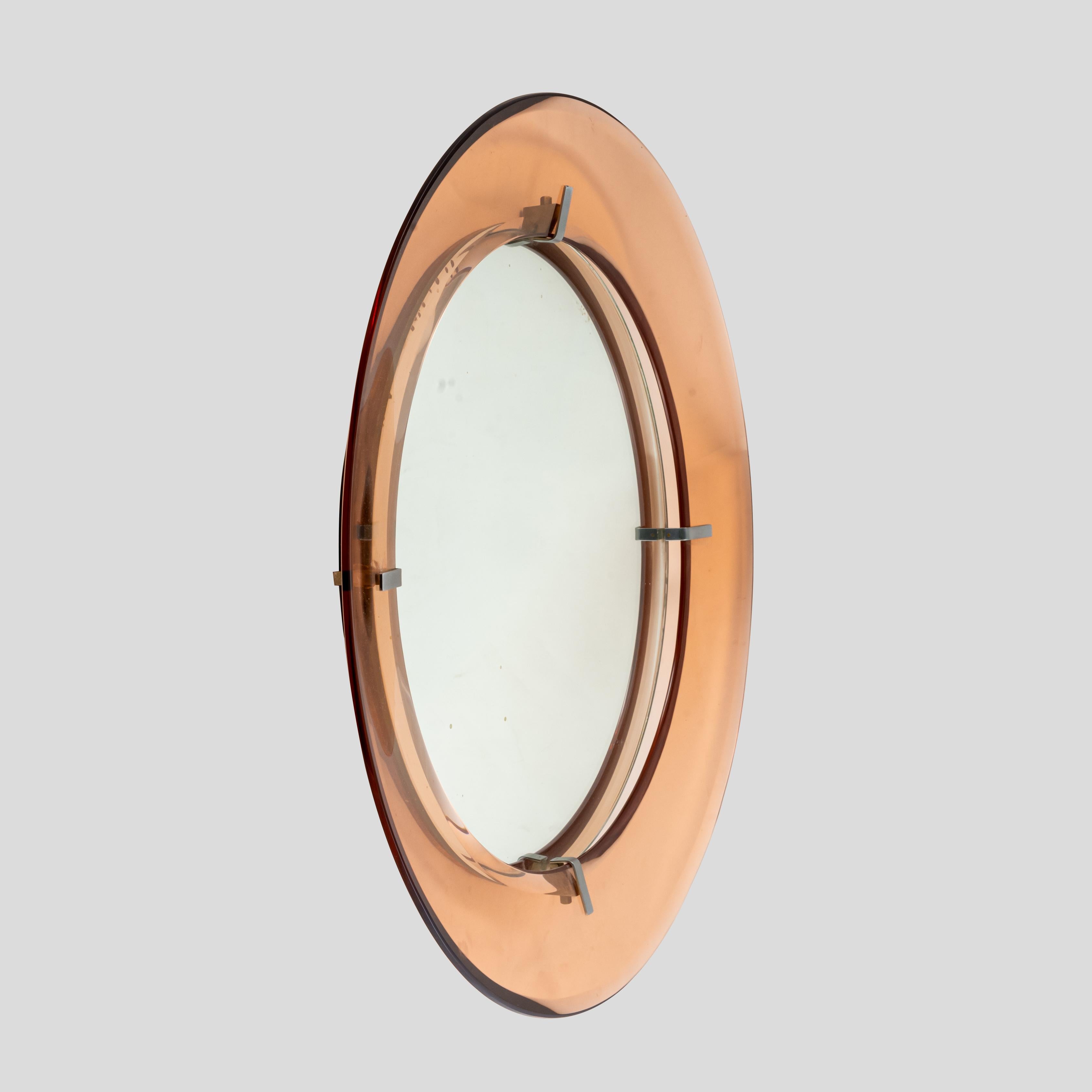 Precioso espejo circular modernista de mediados de siglo, de cristal redondo cóncavo transparente de color melocotón, unido al espejo redondo de la parte posterior por cuatro soportes de metal cromado.

Este espejo se compone de dos partes situadas