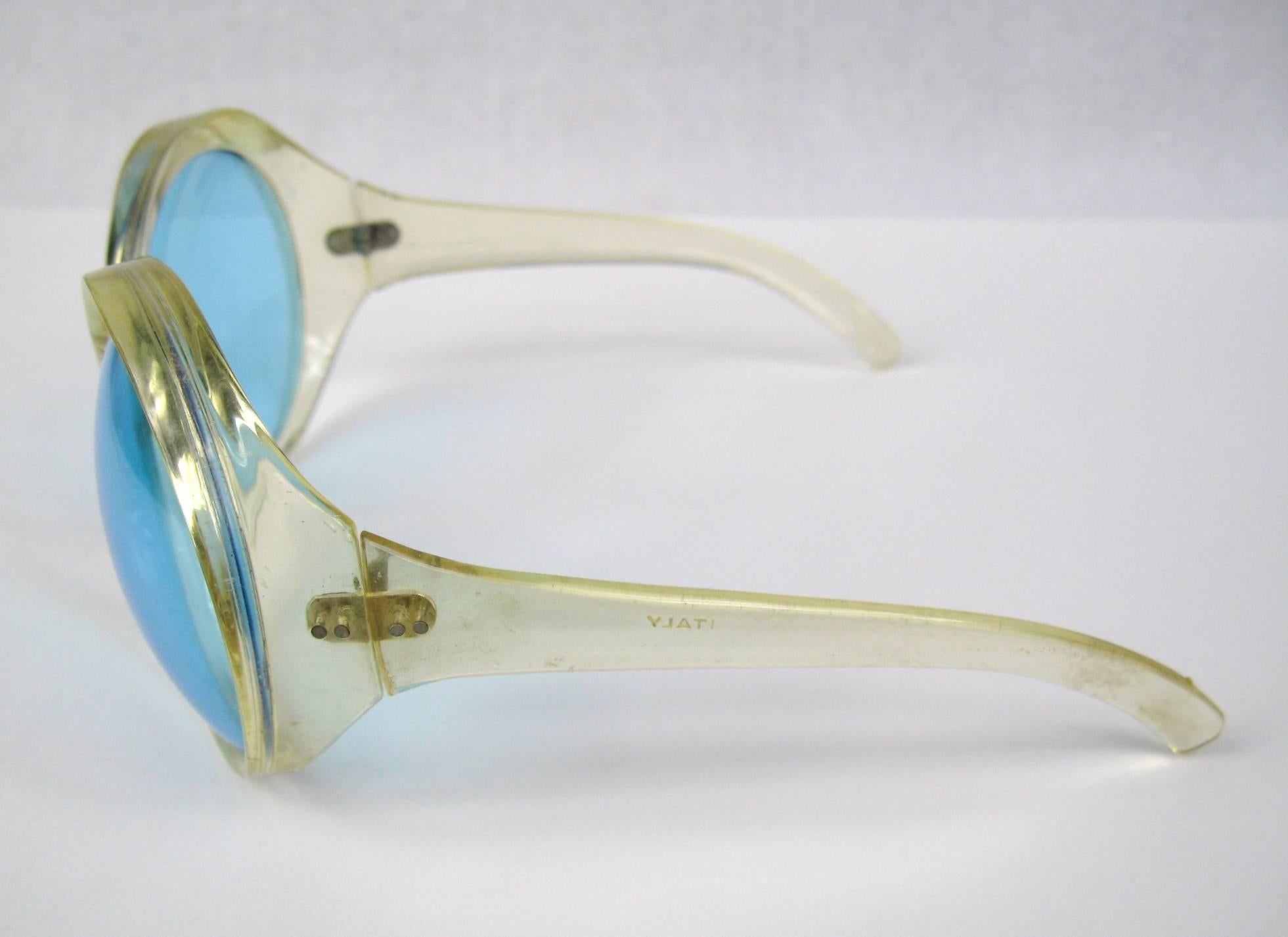 Stunningly large, Clear frame, bug-eye sunglasses Blue lenses Oh so Bridget Bardot from the 1960s. Made in Italy. Excellent vintage condition. Measuring 3.20 x 2.80 top to bottom. Be sure to check our storefront for more fabulous pieces from this