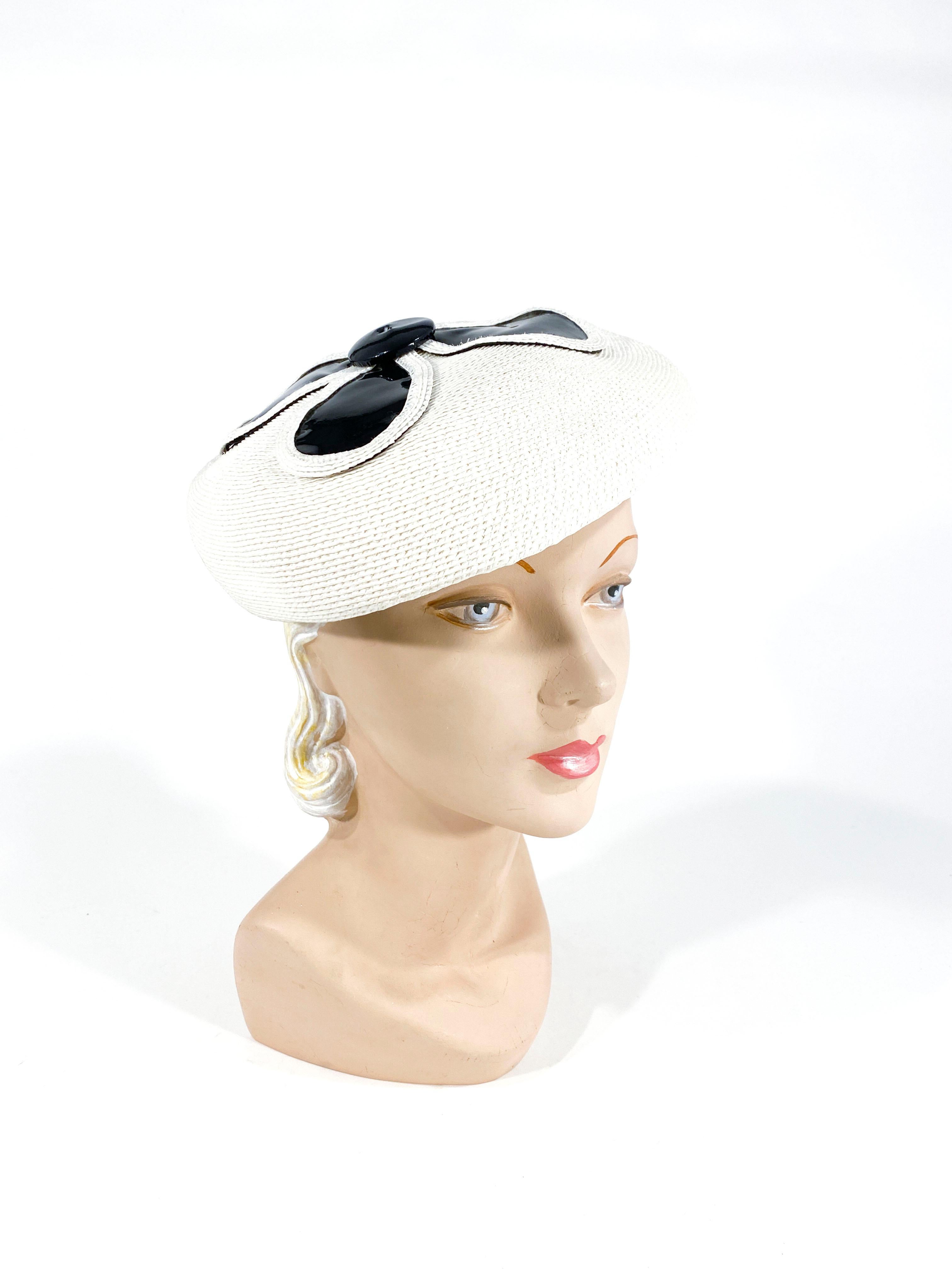1960s mod white coated woven straw beret style hat with navy blue patent leather accents. 