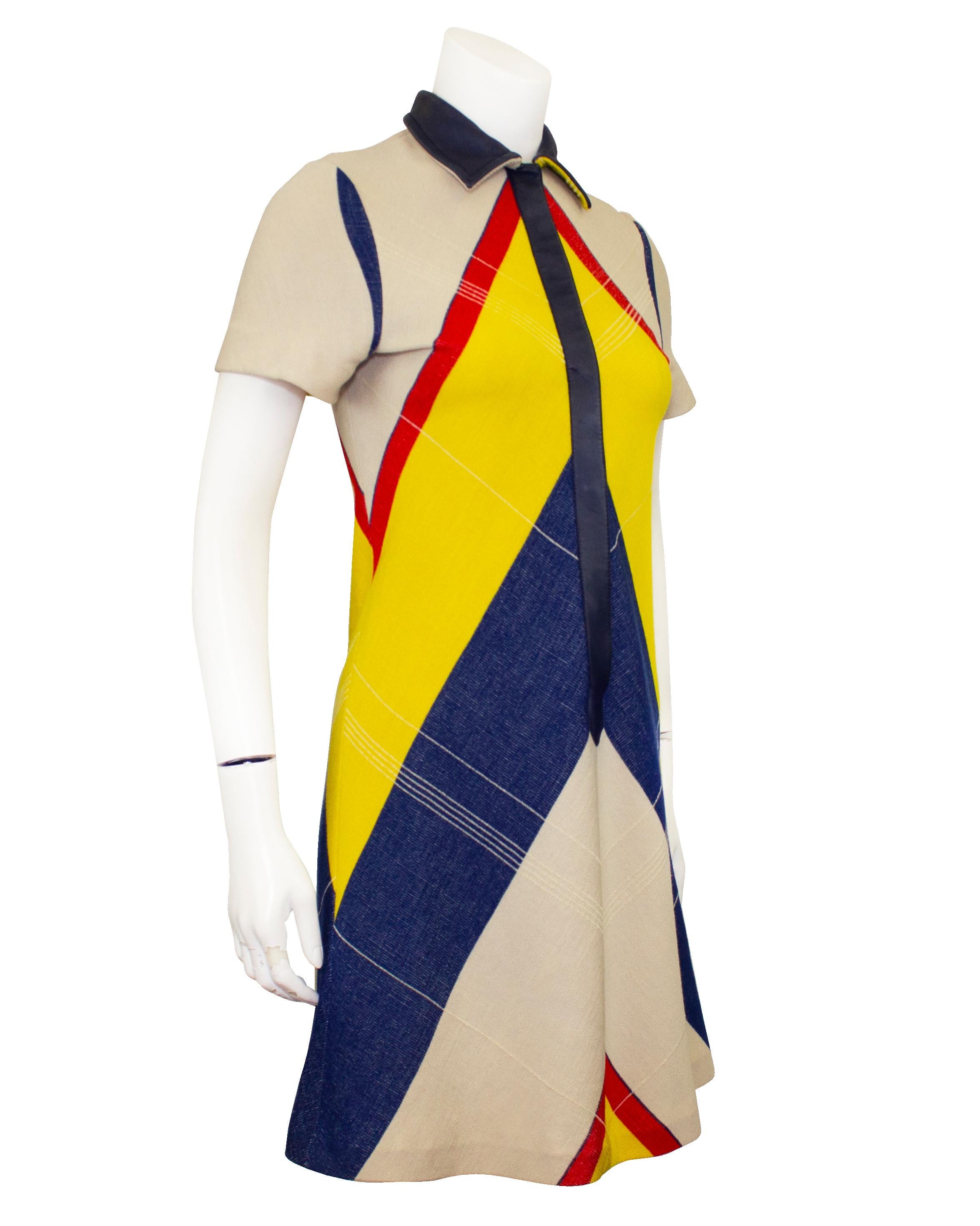 Adorable wool and cotton blend collared shift dress from the Mod look era 1960s. The yellow, red and navy chevron pattern accentuates the flared shape of the dress. Snaps up the front with a navy leather trimmed placket and collar, this dress is