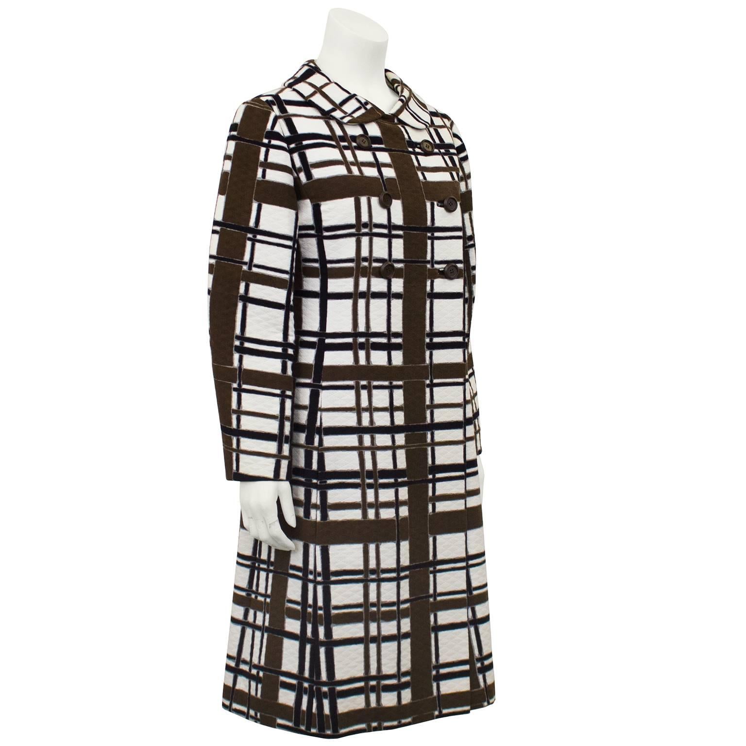 1960s Mod style windowpane print coat. Cream cotton like fabric with quilting throughout with a brown, black and grey windowpane print. Large Peter Pan collar, double breasted with round brown plastic buttons and off white lining. Excellent vintage