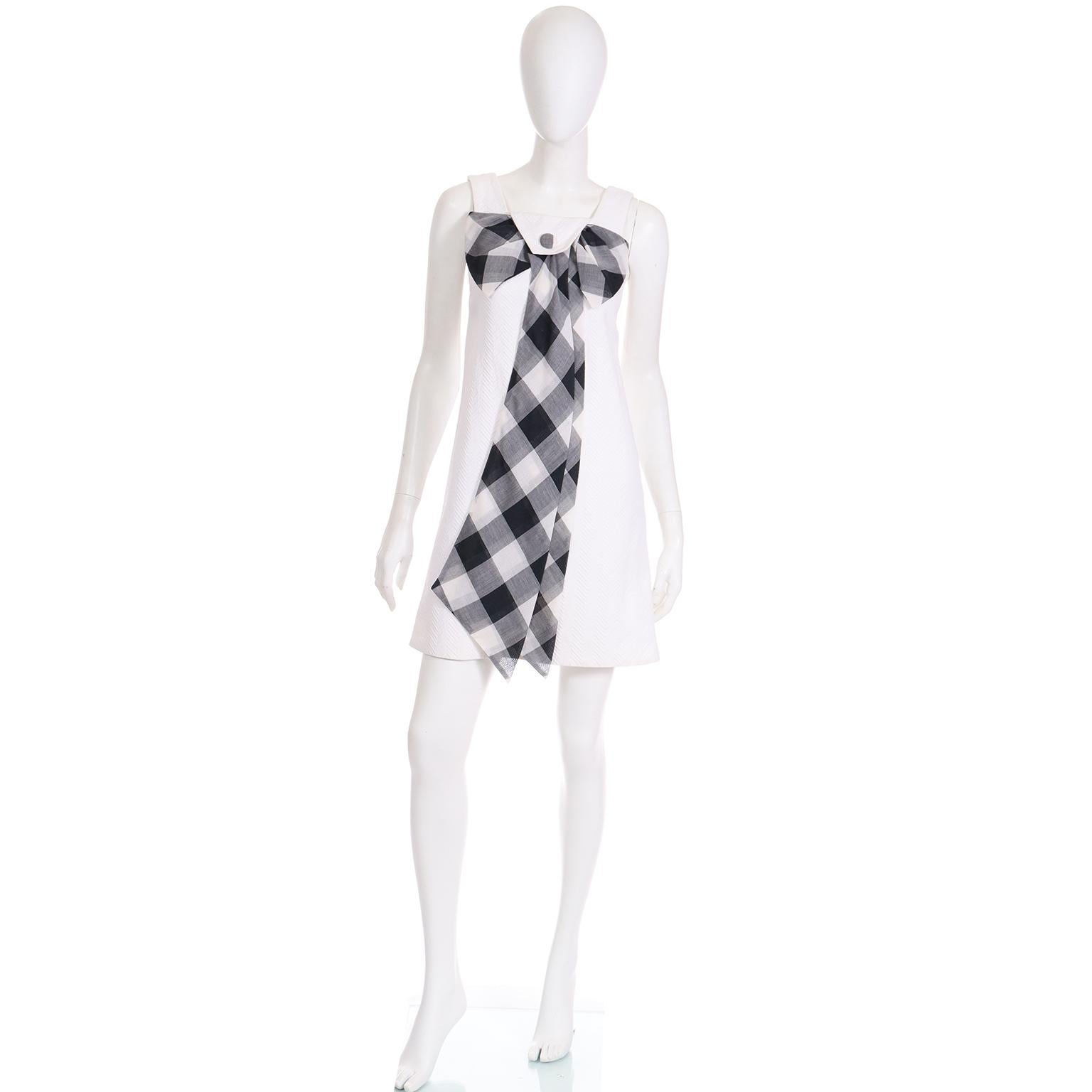 This is a really fun vintage 1960's white cotton pique dress with a dramatic black and white plaid voile bow with a double sash that extends to the hem. There is even a plaid covered button on a flap that goes over the top of the bow as an added