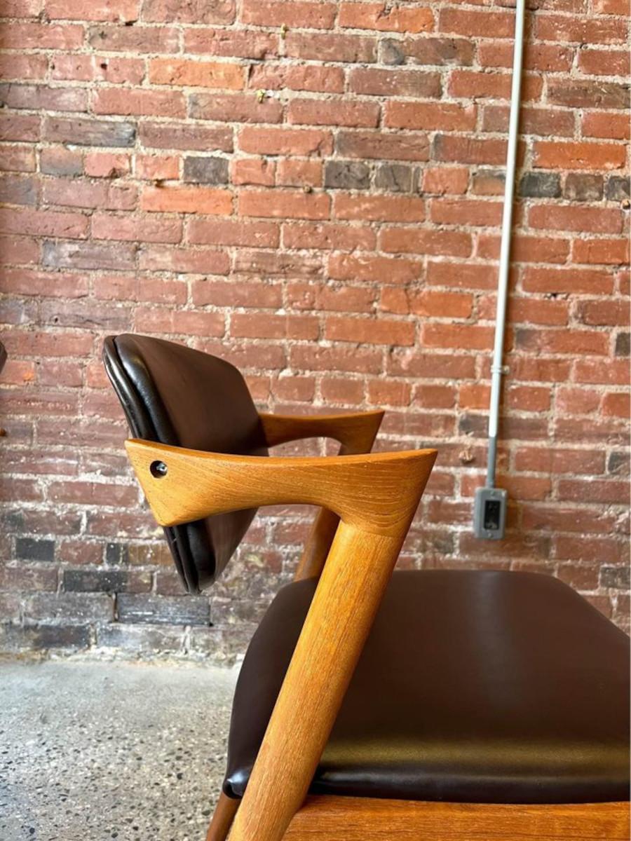 We're thrilled to introduce a magnificent pair of vintage teak side chairs: the iconic Model 42 chair designed by Kai Kristiansen for Schou Andersen in the 1960s. These chairs boast a distinctive elbow rest that gracefully flows down creating a Z