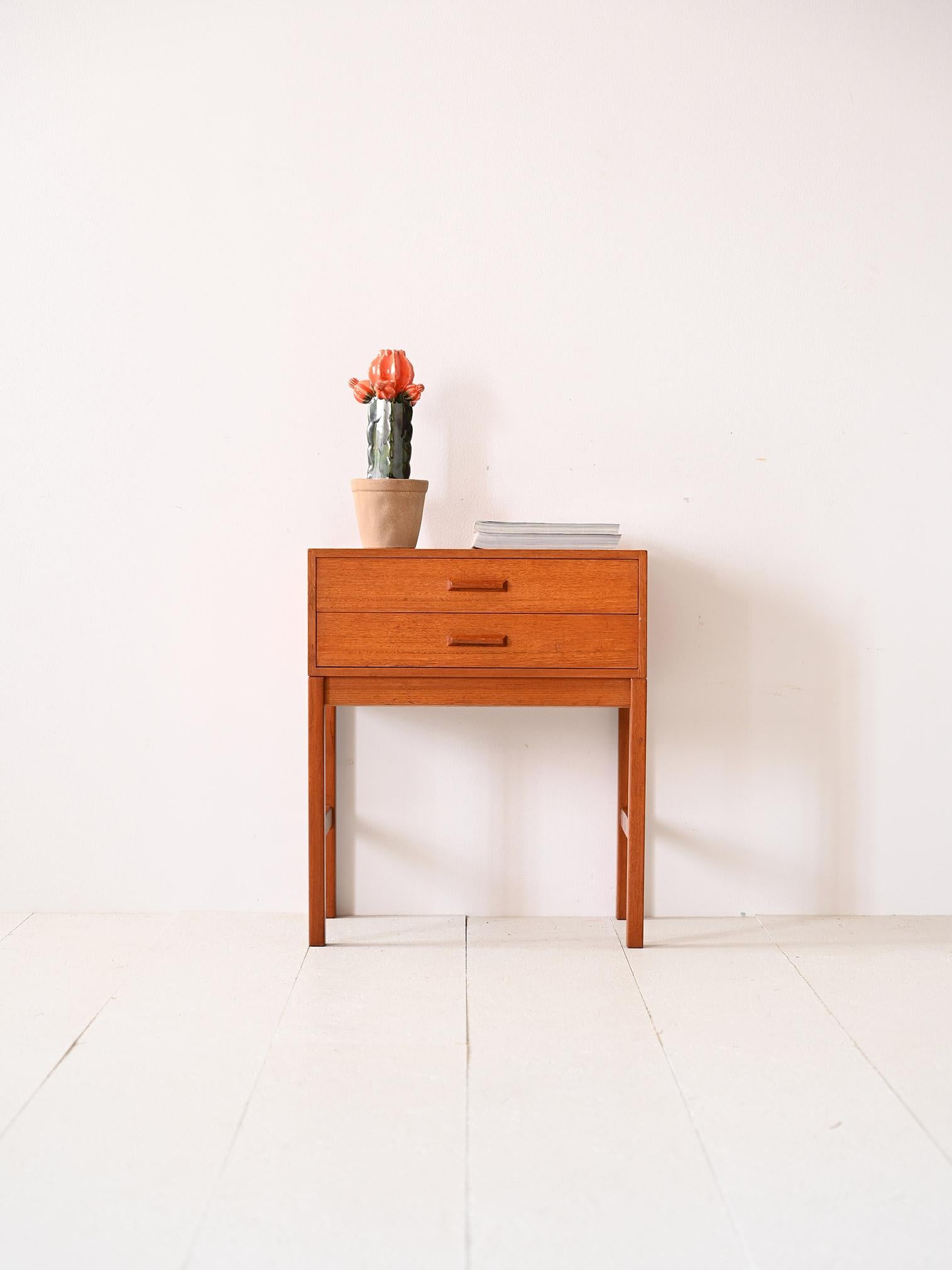 Scandinavian square teak coffee table.

This piece of modern Scandinavian furniture is distinguished by the regular, square lines that make up the top and the long legs. The two drawers feature a wooden handle, also with a defined cut-out.
Perfect