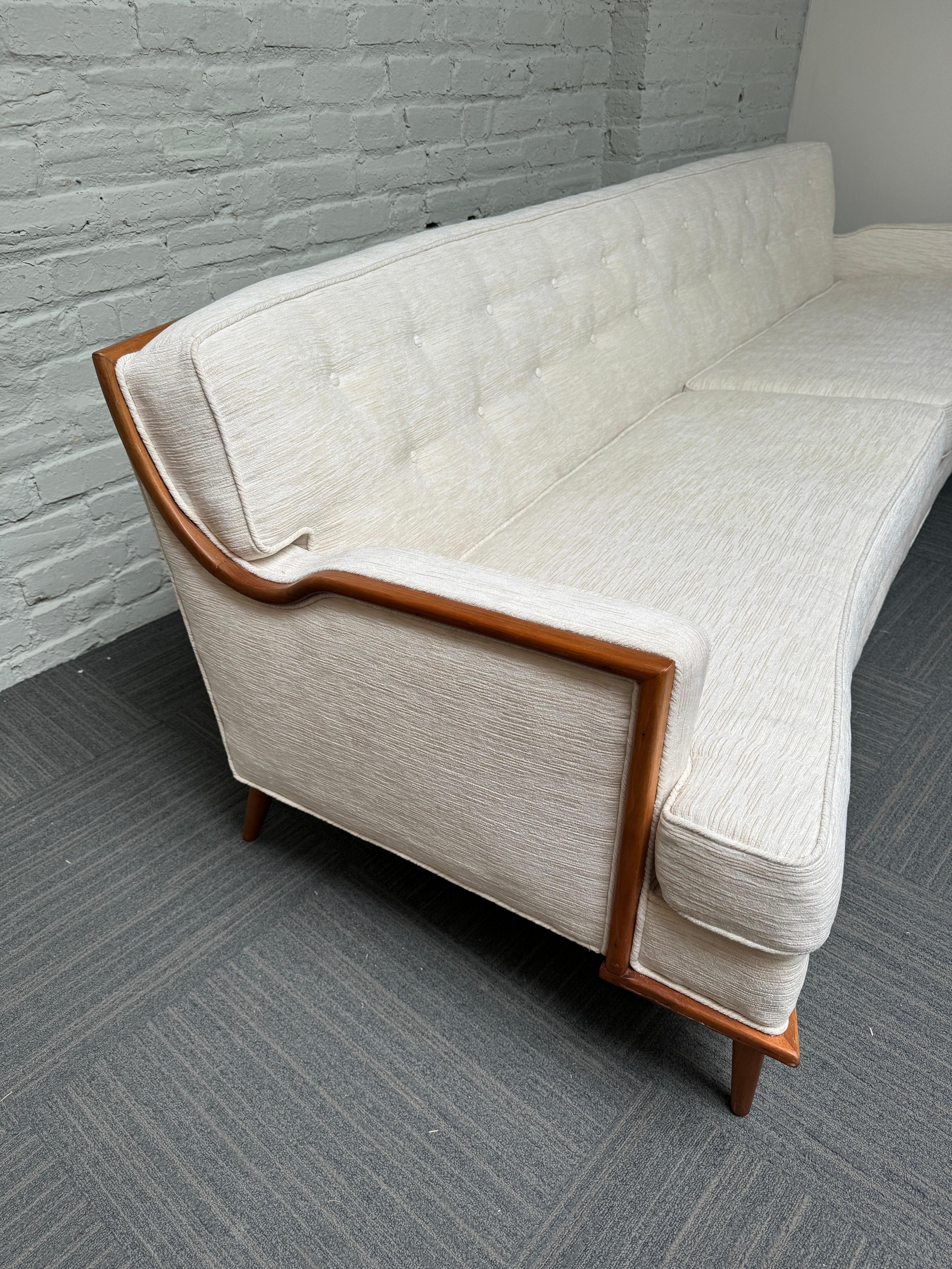 Ce canapé à dossier incurvé de style Adrian Pearsall, datant des années 1960, est absolument magnifique. Il est attribué à la société Baker Furniture Company. La pièce présente un cadre unique en noyer apparent et des pieds avant doubles (7 pieds au