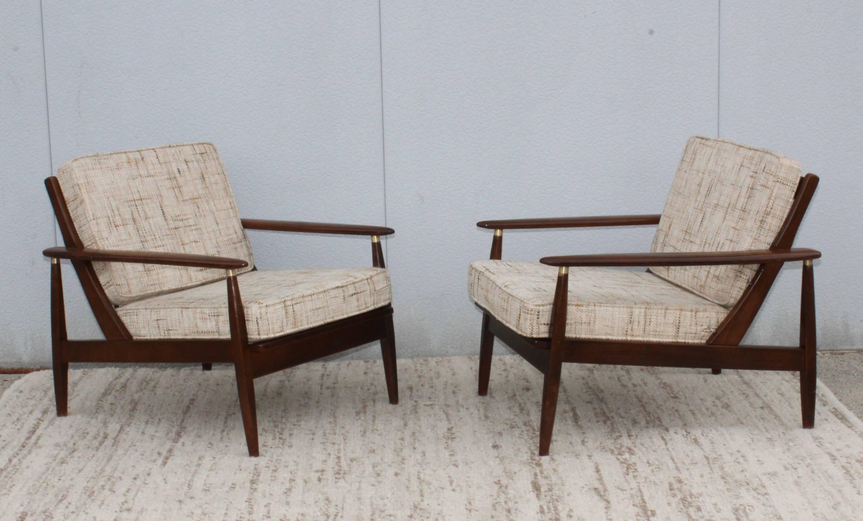 1960s modern walnut lounge chairs with brass detail.