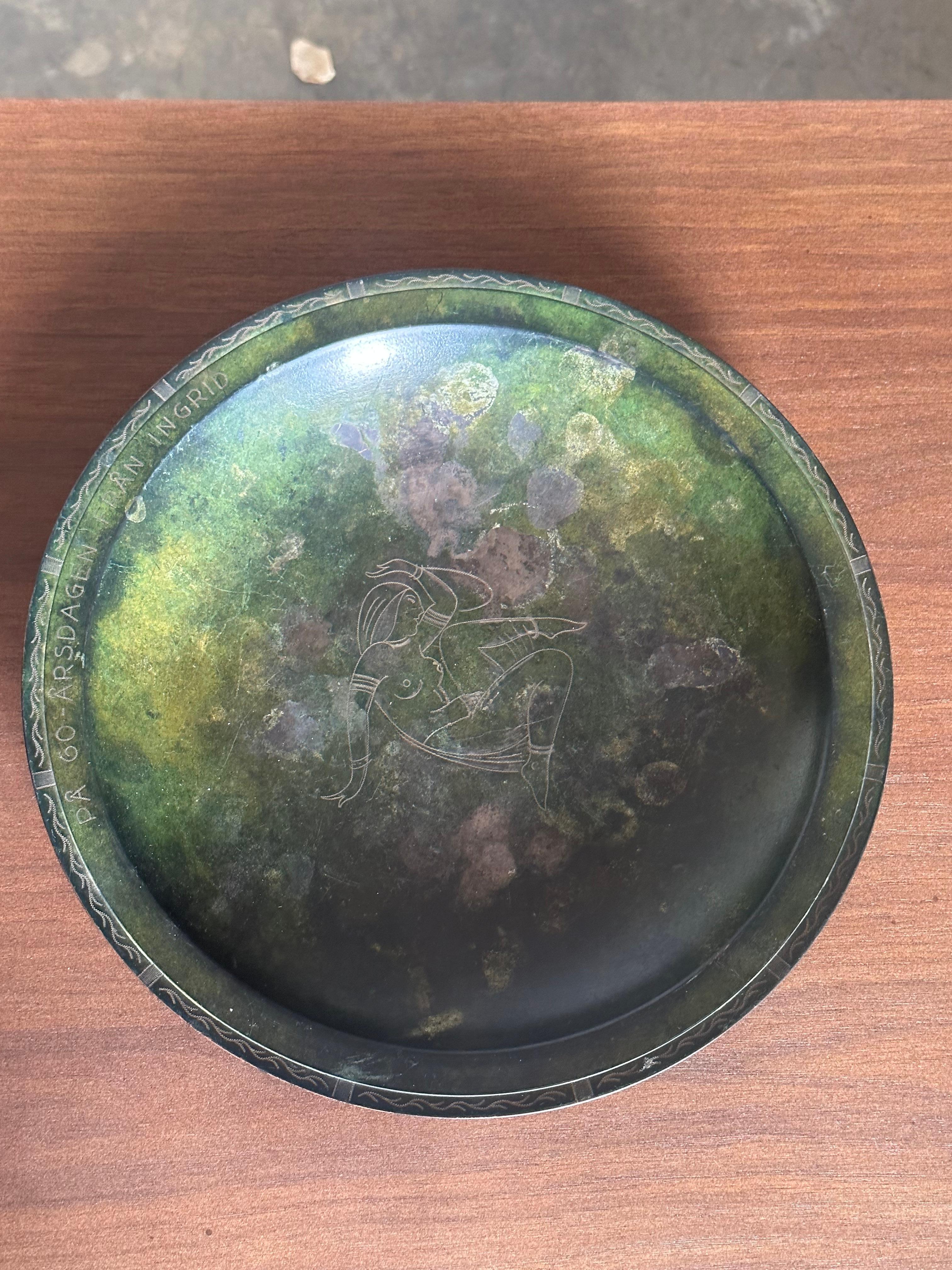 A vintage bronze low bowl with heavy patina. Classic minimalist bronze bowl with a nude motif in the middle and subtle pattern to border. Engraving to one side. 