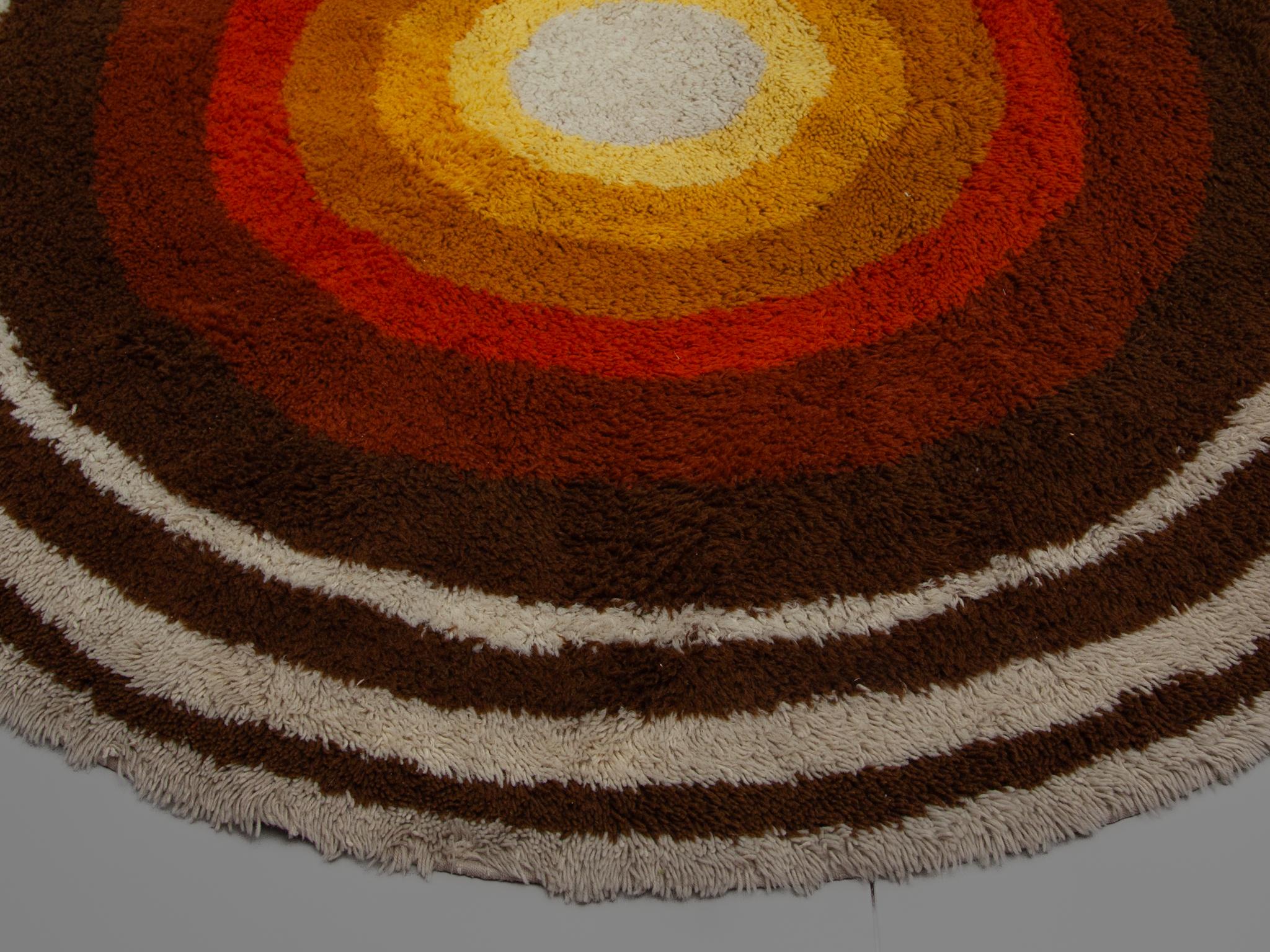 1960s Modernist round carpet by Desso, designed in the Netherlands, Pop art period. It is made from polyacryl wool and it is still in a very good vintage condition. Beautiful bright colors in several brown, orange and yellow tones. 

An interesting