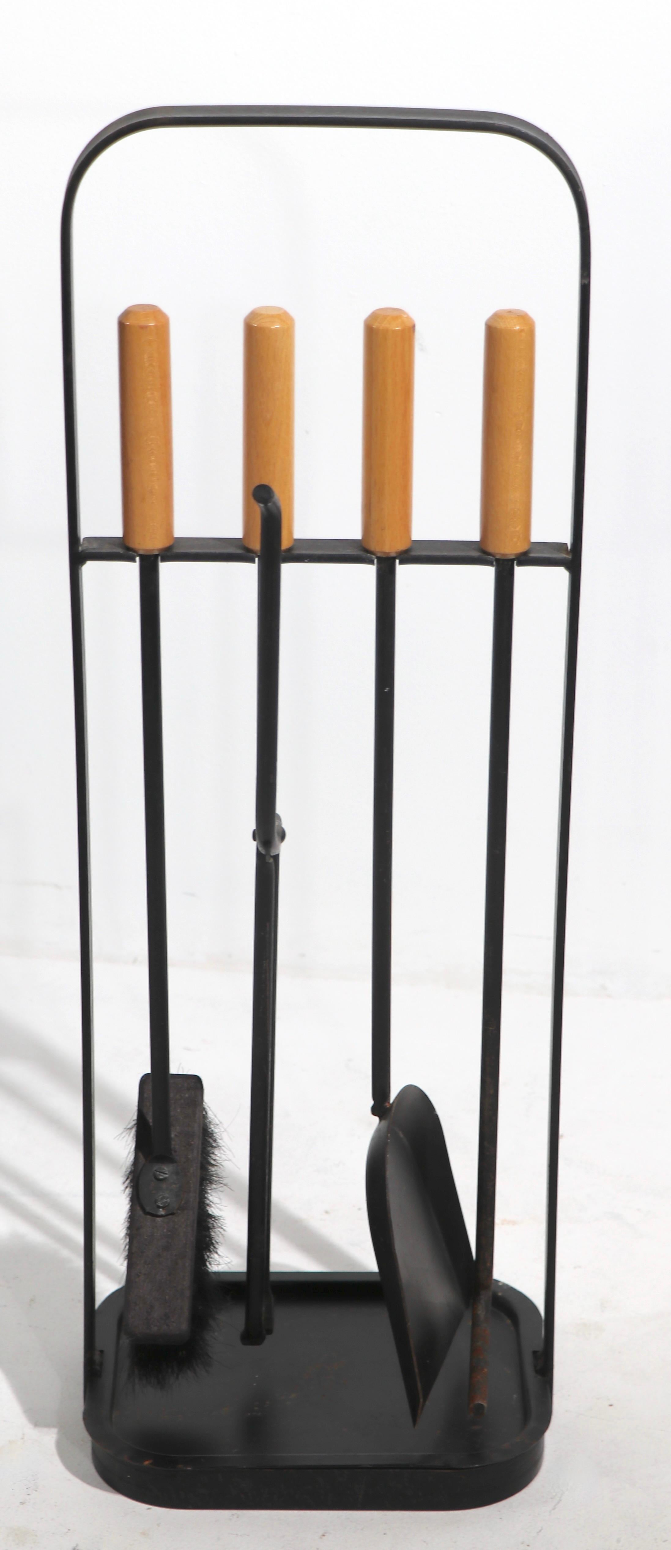 Stylish and whelk crafted freestanding fireplace tool set, of wrought iron and wood. This set consists of four tools, brush, shovel, tongs and poker, and the stand. This example is in very good original condition, clean and ready to use.