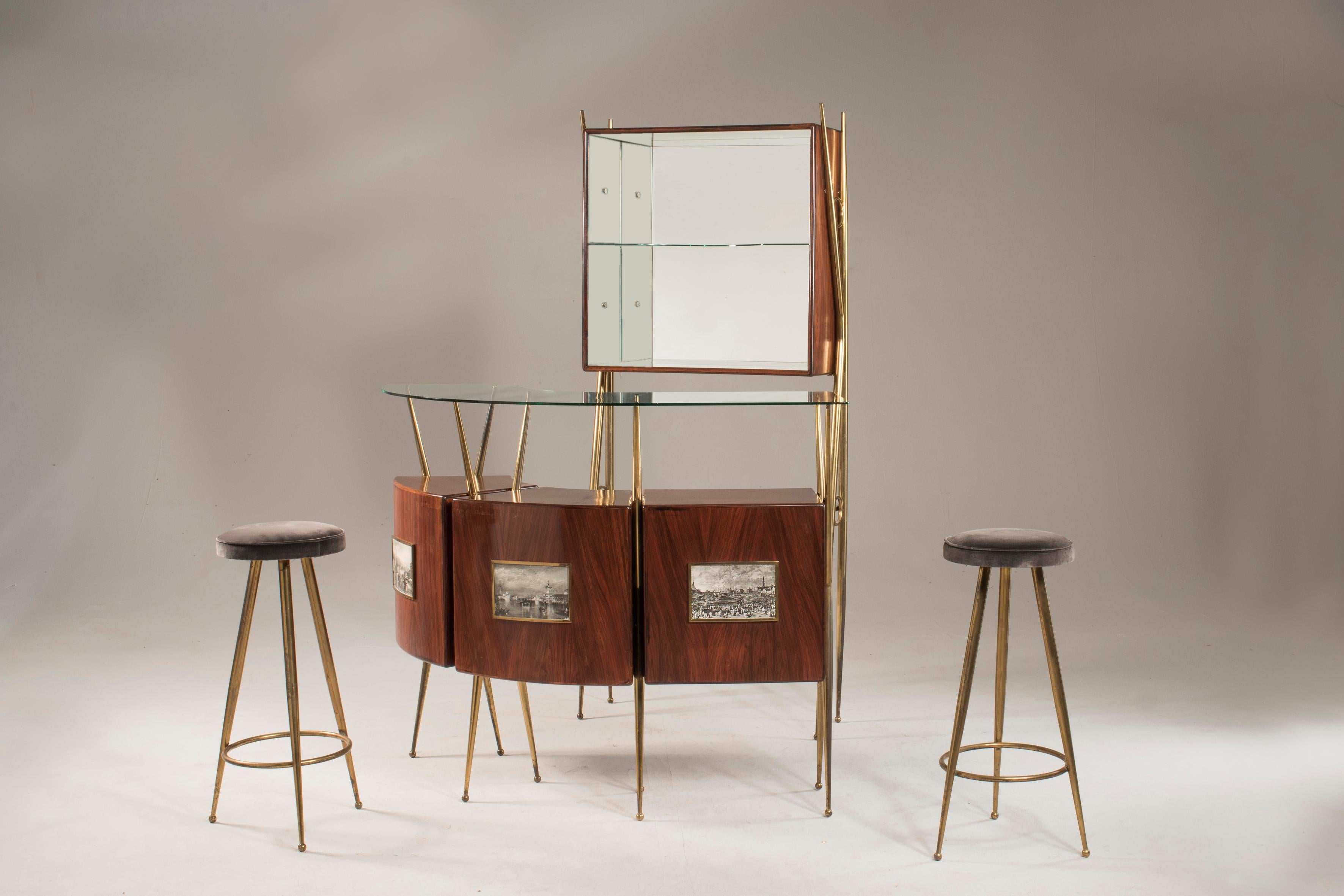 Midcentury cocktail bar set with mirrored display cabinet and two stools, at the manner of Gio Ponti. The bar cabinet features three individual rosewood sections with a floating glass top, mounted on brass patinated X frames. The concave rear