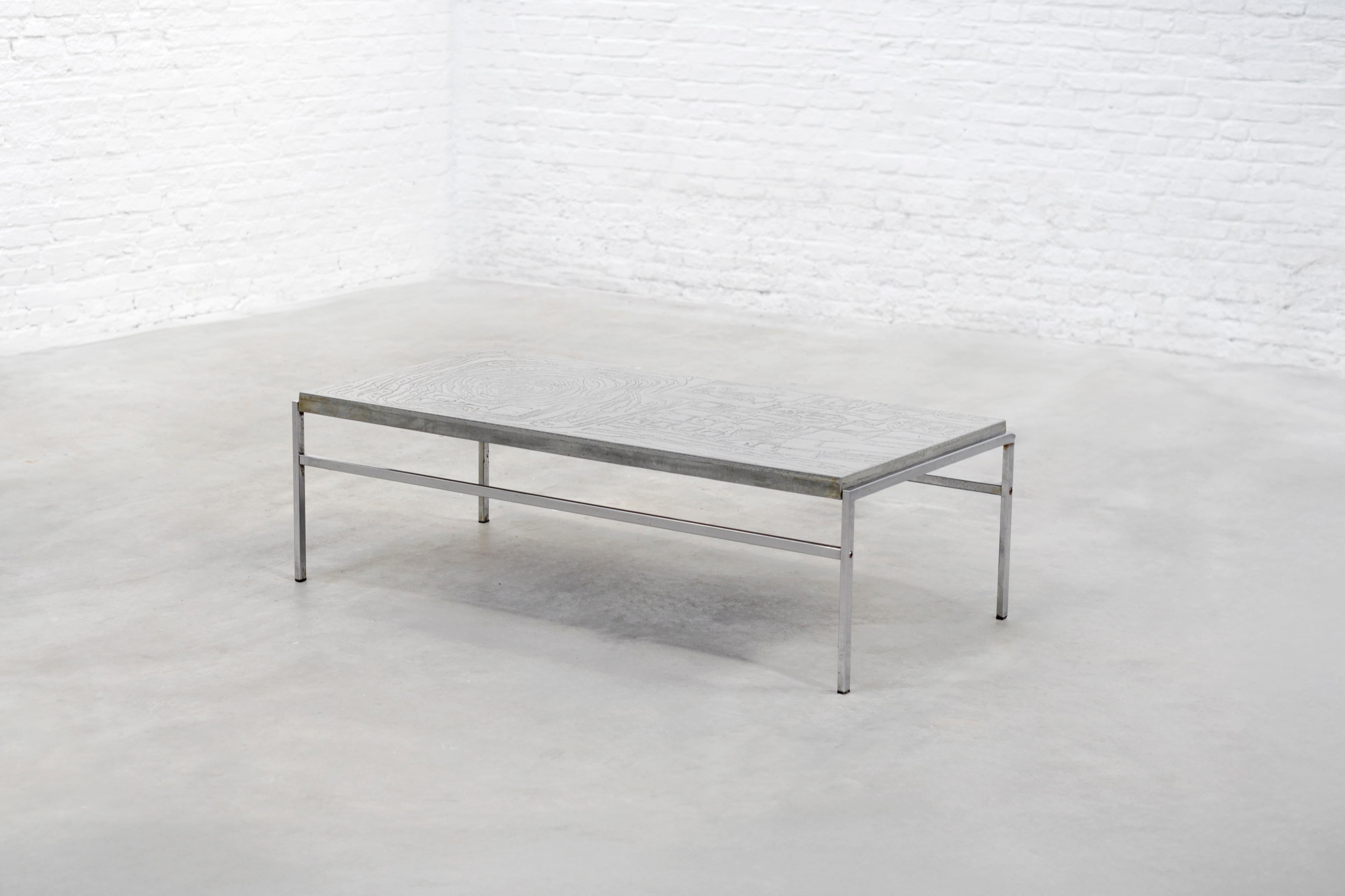 Table basse moderniste des années 1960, caractérisée par une structure métallique minimaliste et un plateau texturé. Le design met l'accent sur des lignes épurées et une simplicité fonctionnelle, reflétant les principes du modernisme du milieu du