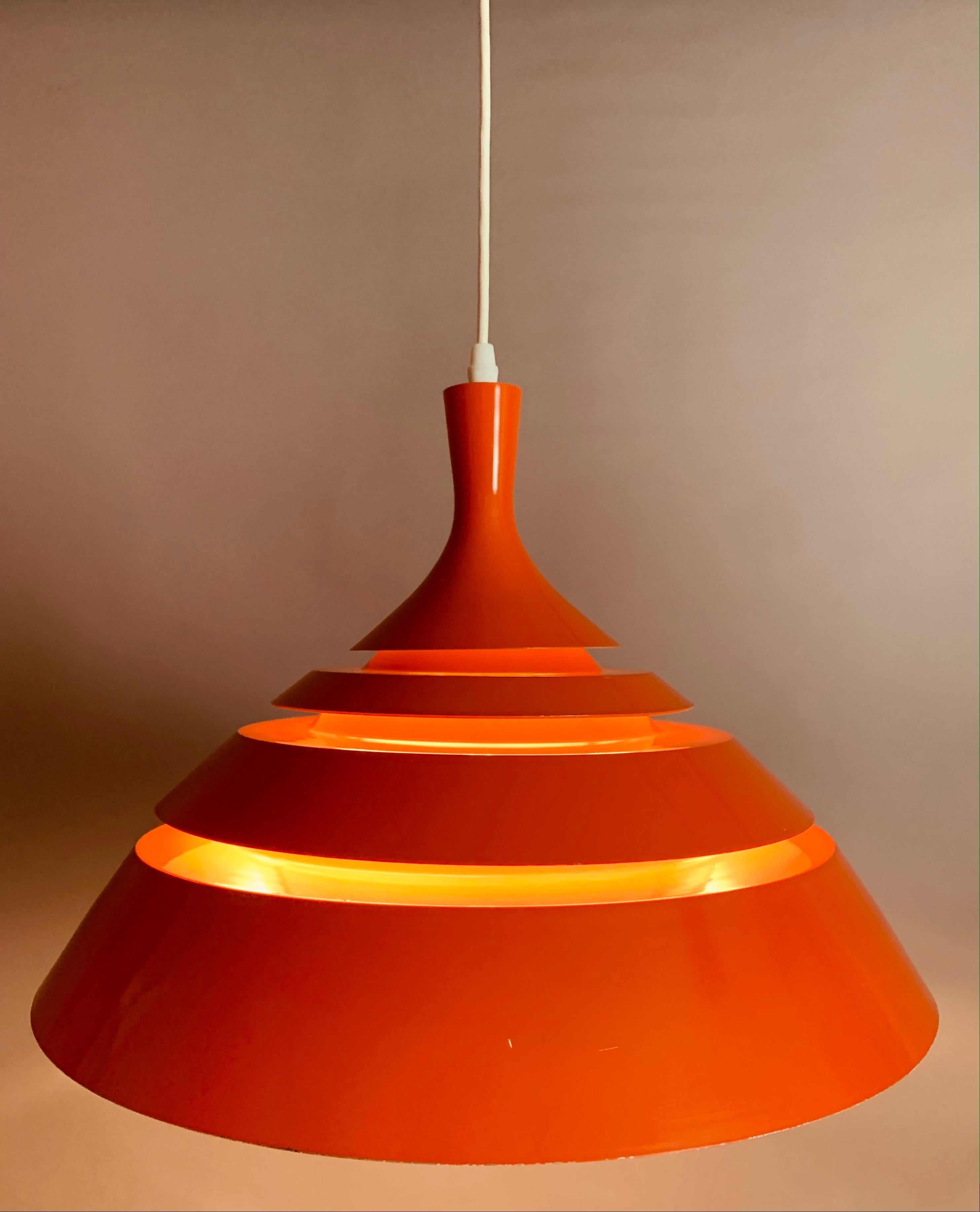 An unusual, space-age, modernist, hanging ceiling light. Designed by Hans-Agne Jakobsson during the 1960s in Sweden. The light is constructed from orange lacquered metal blades suspended from a white metal interior frame. The light shines through