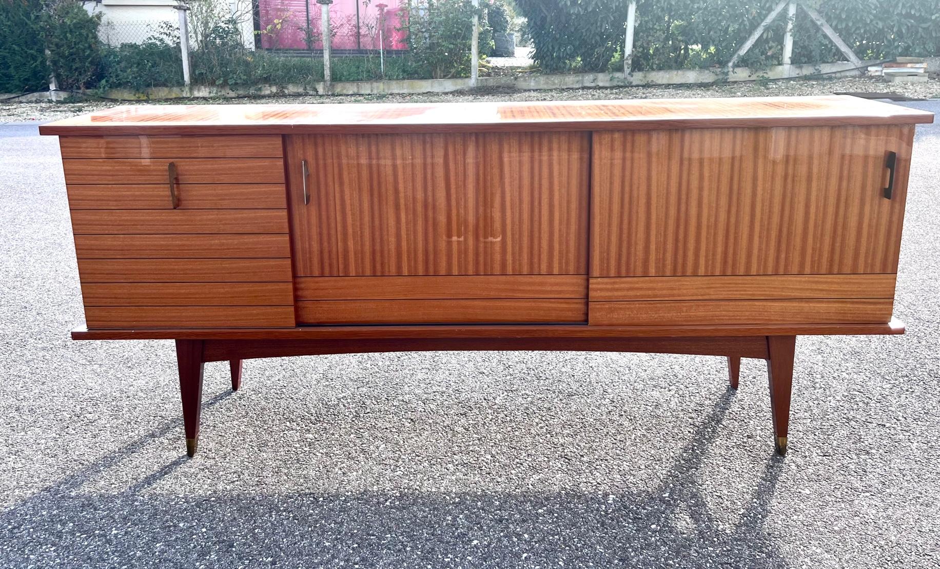 Beautiful cabinet from the 1960's with two sliding doors and one drop down door.
Wood shelves behind the sliding doors and one glass shelf on the left 
Ebonized decor in between the teak veneers giving the piece a very graphic and modern look.