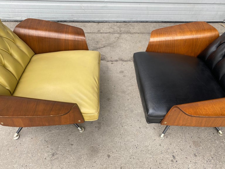A stunning pair 1960s lounge chairs by Murphy Miller. Button tufted upholstery, these gently used swivel lounge chairs boasts winged walnut armrests and original vinyl upholstery. Nice original condition.. A vintage gem that has an unusual swivel