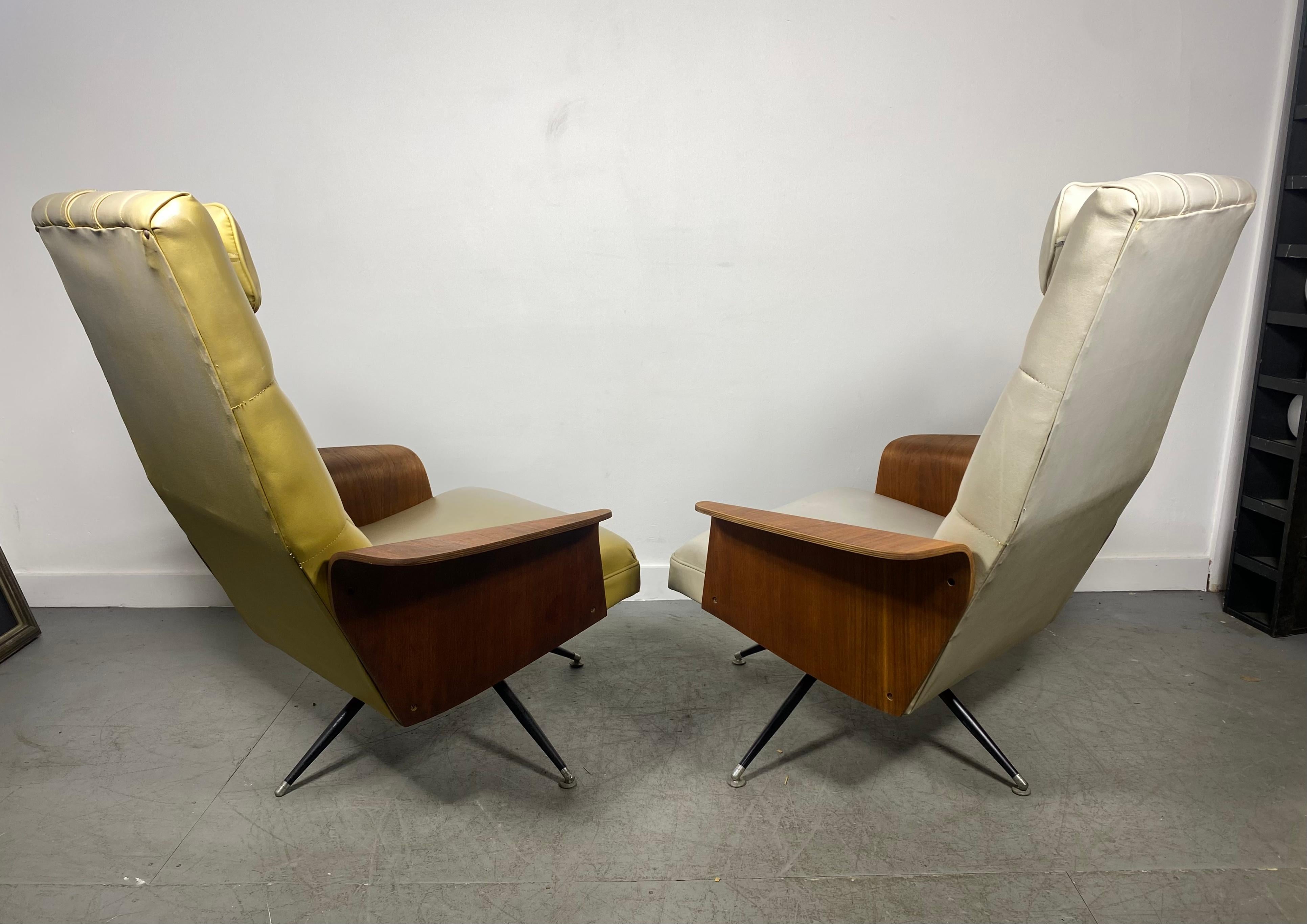 A stunning pair 1960s lounge chairs by Murphy Miller. Button tufted upholstery, these gently used swivel lounge chairs boasts winged walnut armrests and original vinyl upholstery. Nice original condition.. A vintage gem that has an unusual swivel