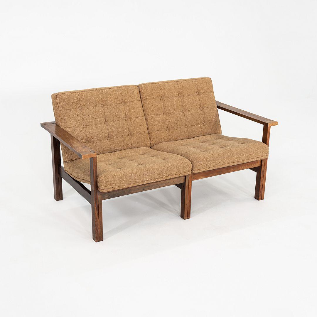 Si tratta di una poltrona Moduline, disegnata nel 1962 da Ole Gjerlov-Knudsen e Torben Lind per la danese France & Son. La struttura è in legno di palissandro e i sedili sono rivestiti in un materiale marrone tweed. Il legno utilizzato per i