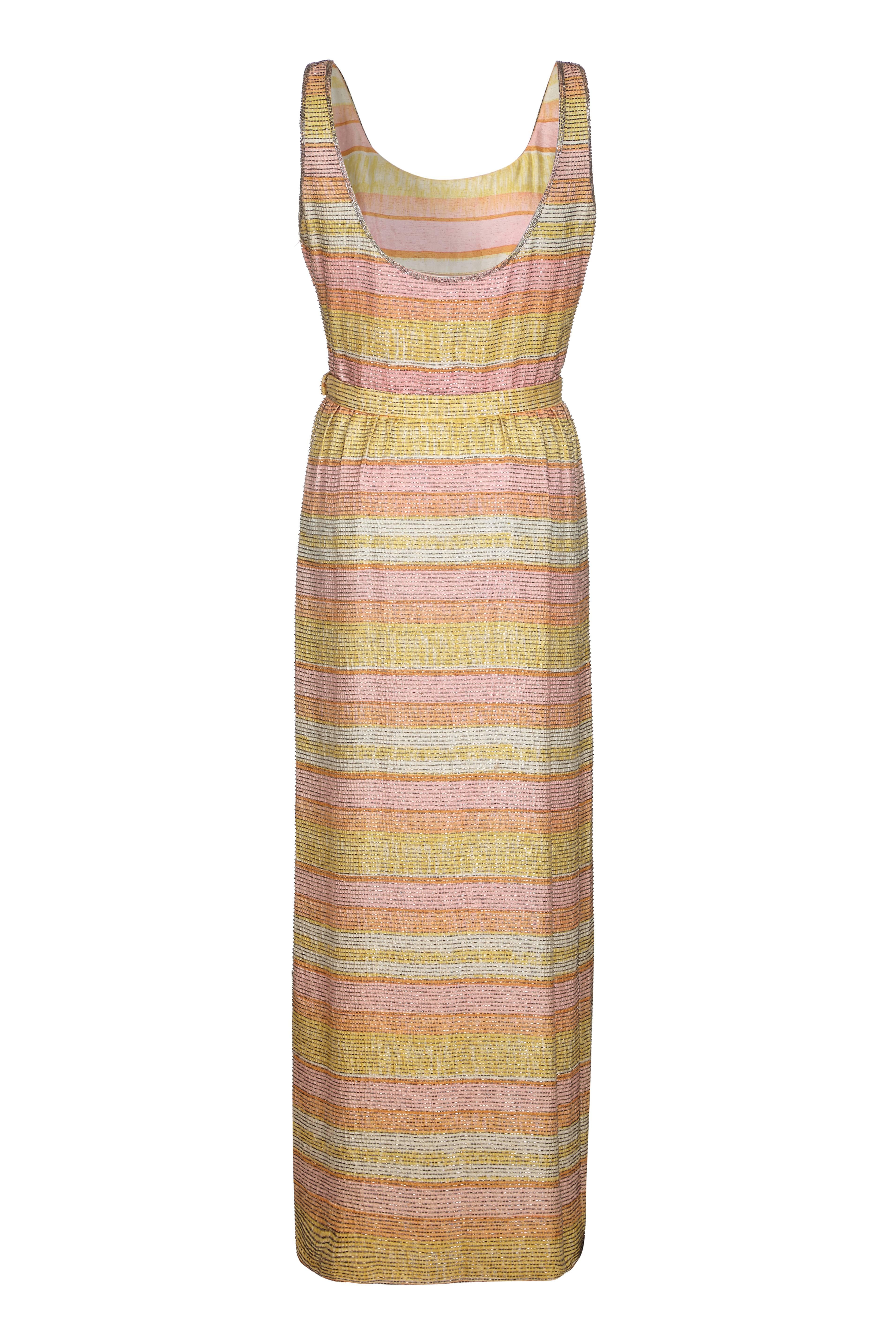 Increíble vestido vintage de seda de los años 60 de Mollie Parnis, de bonitas rayas pastel con abalorios por toda la prenda.  Es de largo completo, con una abertura a un lado de la falda, cinturón en la cintura y cierre de cremallera lateral. Una
