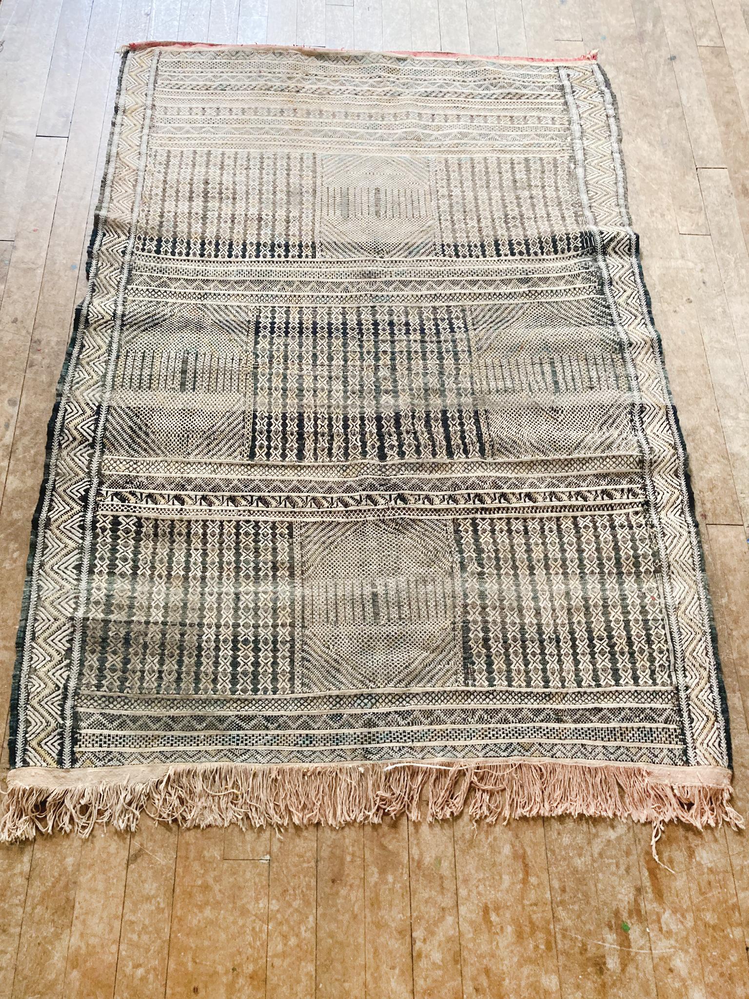 Richly textured Moroccan area rug with a primarily black-and-white palette punctuated with hints of red, yellow, and blue. Geometric patterns make up the bold design. The rug is beautifully aged.

Dimensions:
6' 10