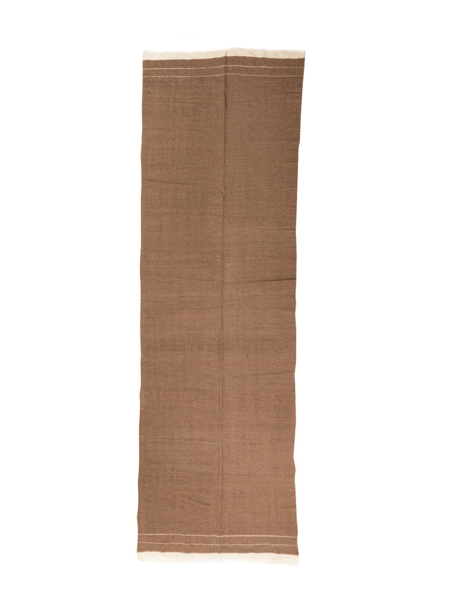 A Moroccan flat-weave runner, handwoven in the 1960s. Warm brown tone with frills in a beige white. Elegant, minimal patterning at either end. A series of bands in the same beige color.

Dimensions:
15' 3