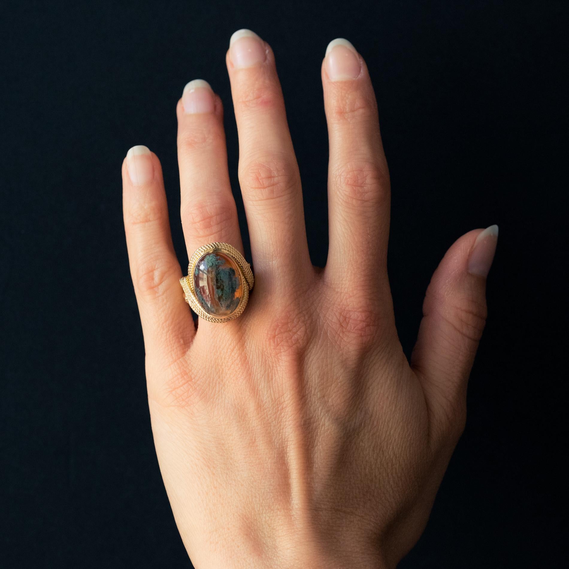 Ring in 18 karat yellow gold, weevil hallmark.
Important retro ring, it is formed by a ribbon composed of three twisted gold threads which hold on top and in closed setting, an orange moss agate. The entire basket also consists of twisted gold