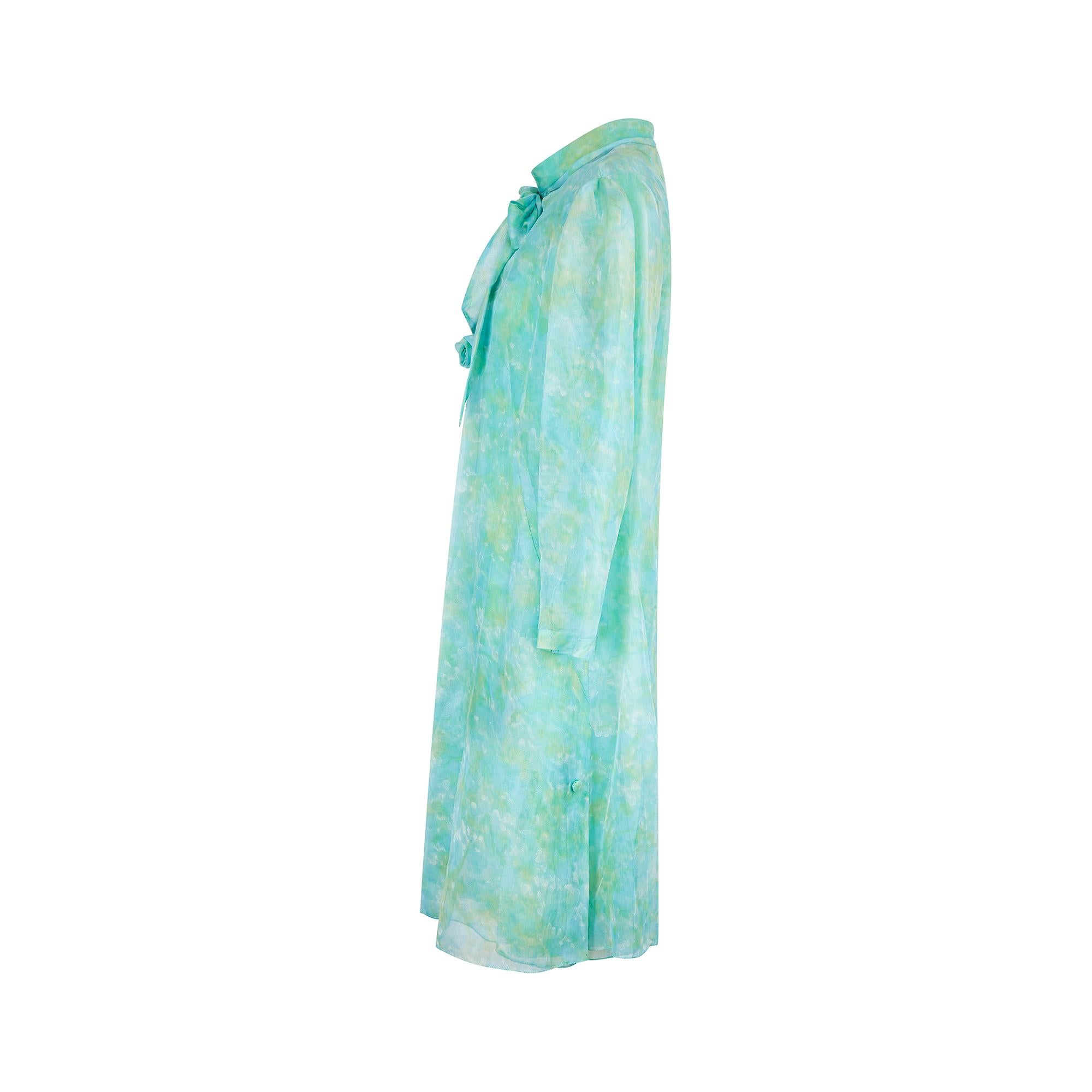 This 1960s dress suit ensemble has intricate detailing that really sets it apart - note the beautiful sunray pleating across the bust anchored by a rose formed from coordinating, mottled blue-green manmade chiffon. The high-neckline is typical of