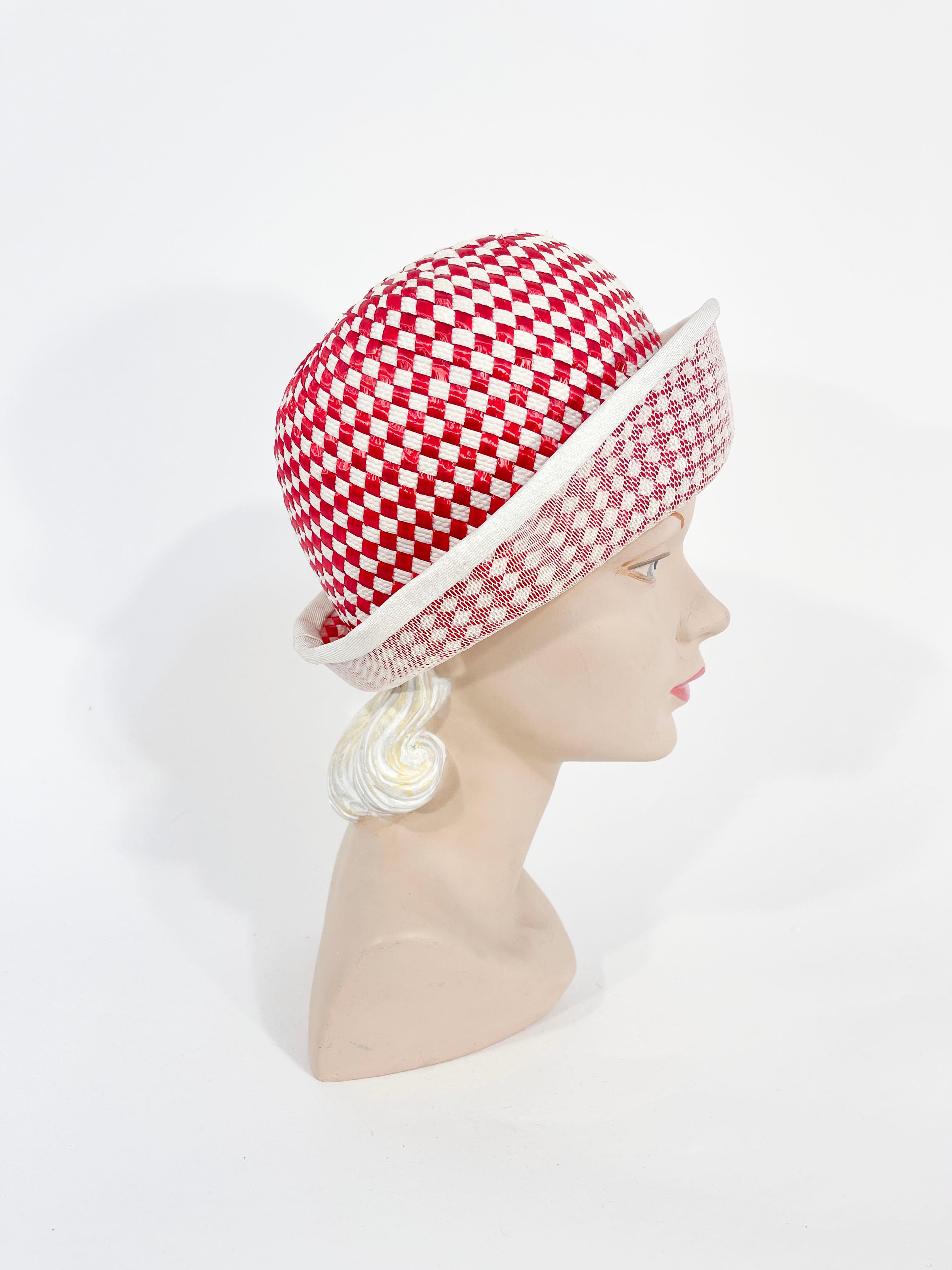 1960s Mr. John red and white woven raffia hat with hand sculpted crown, rolled brim and structured hat base. The rim of the brim has a narrow white band bordering the entire hat. The interior is lined with a structured mesh and finished with a wide