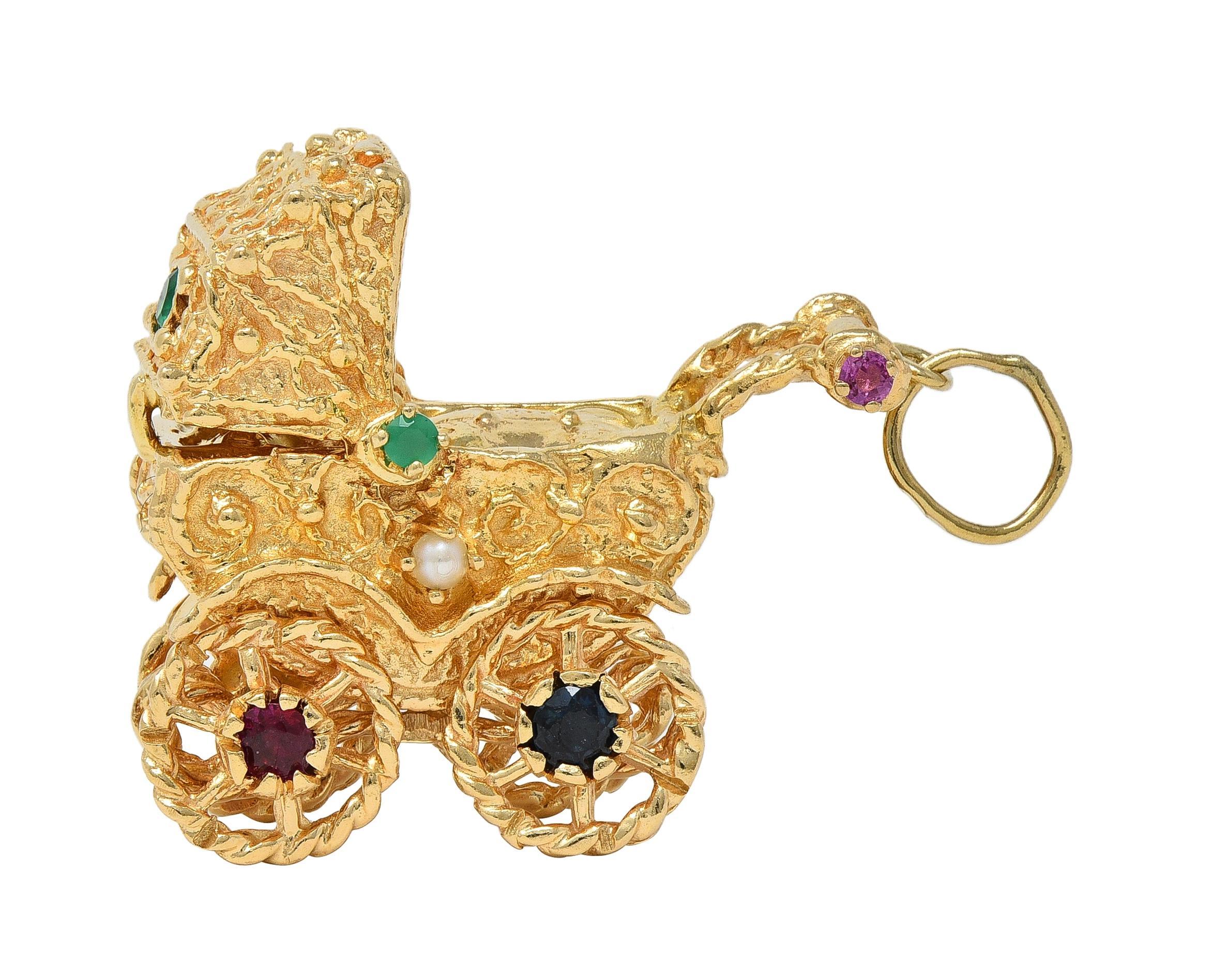 Designed as a highly dimensional baby carriage with grooved texture and scrolling filigree throughout
Featuring spinning wheels and hinged cover that opens and closes over a swaddled baby
Accented by round cut rubies, sapphires, and chrysoprase