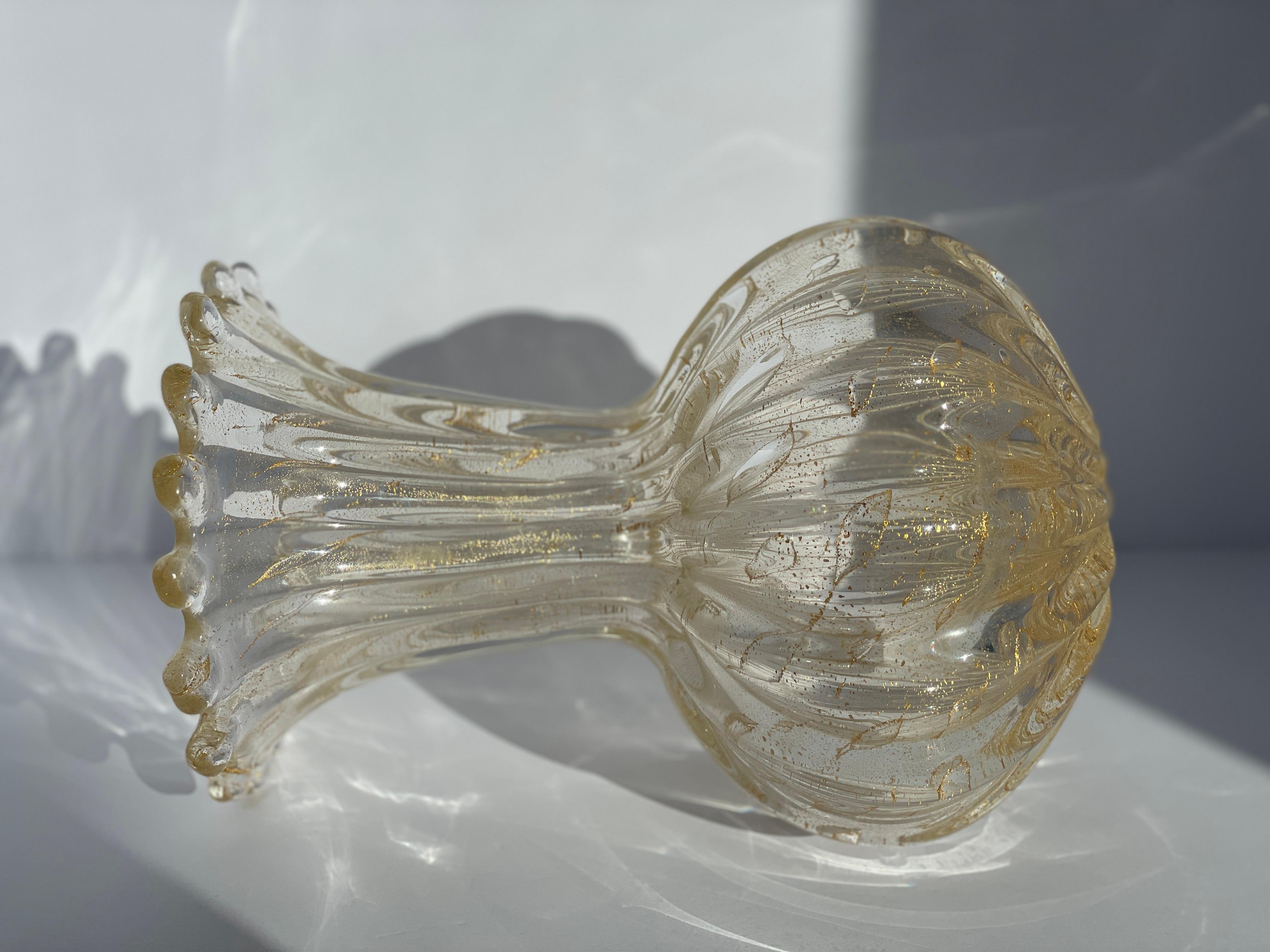 Un vaso in vetro di Murano elegante e senza tempo nello stile di Archimede Seguso, risalente agli anni Sessanta. Questo pezzo presenta un corpo trasparente con foglia d'oro in sospensione, combinato con una superficie a coste e la classica tecnica