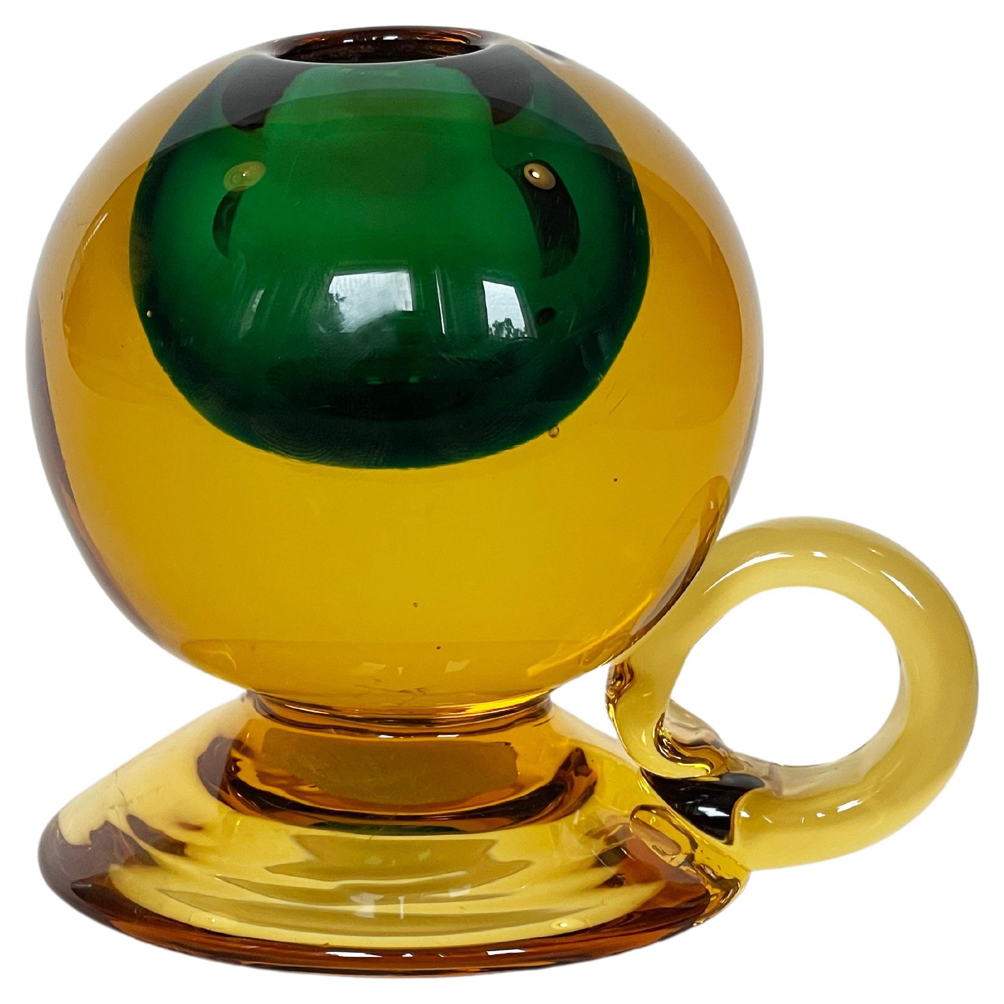 Gorgeous small candlestick by Vetreria Cenedese.
Sommerso hand made glass sphere from heavy chunky Murano art glas.
A many famous artists worked for this maker, this particular piece comes in an amber or golden glow with a dark green inner.
Most