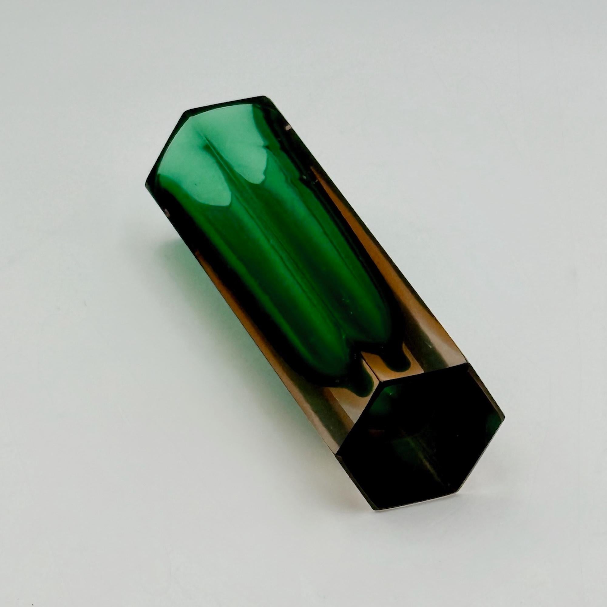 Diese auffällige Vintage-Vase aus Murano aus den 1960er Jahren ist ein Beispiel für die Sommerso-Technik und zeigt einen smaragdgrünen Kern, der in warmes, bernsteinfarbenes Kristall getaucht ist. Seine facettierte sechseckige Form erzeugt fesselnde