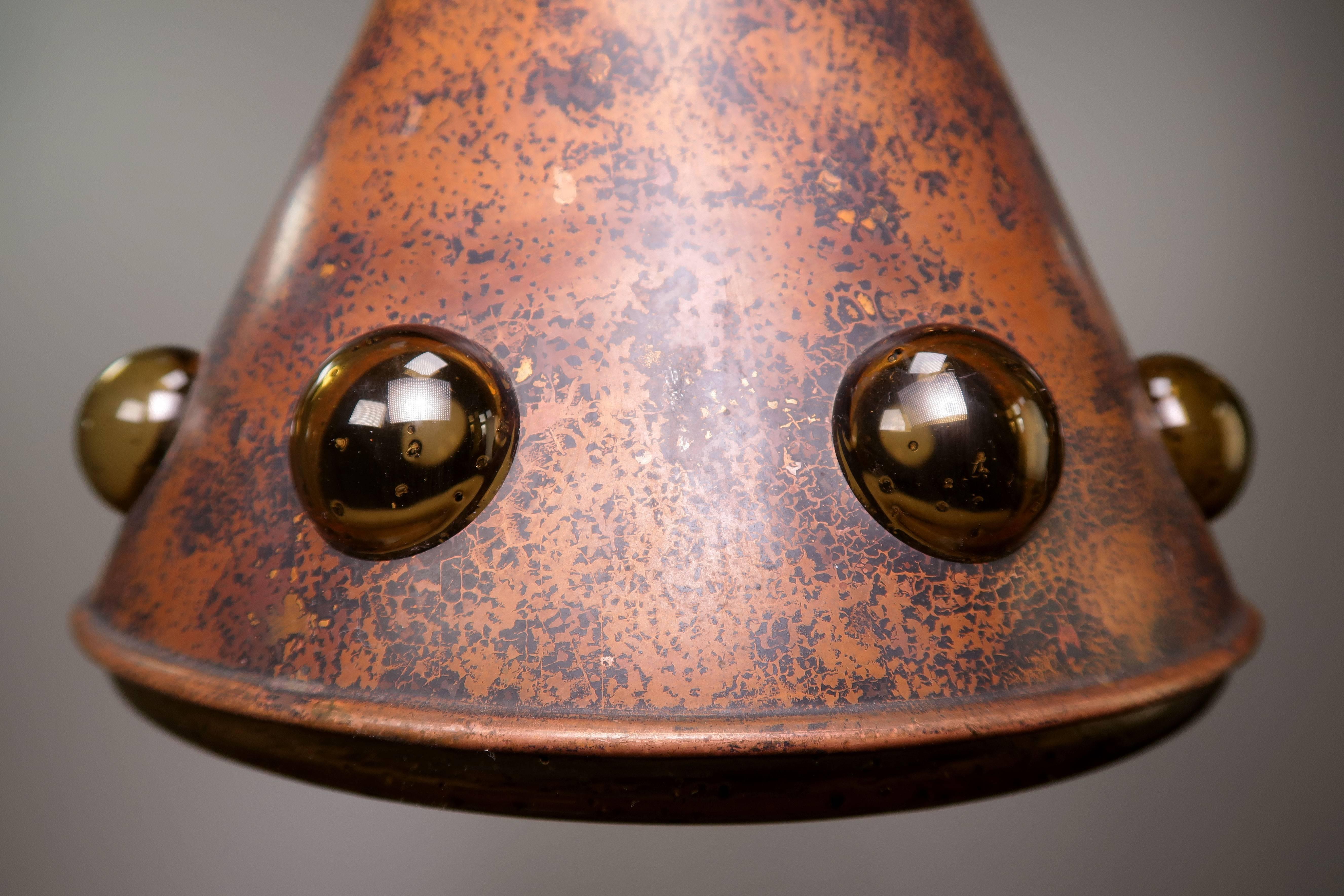 Rustic midcentury modern brutalist 1960s Finnish/Dutch ceiling copper pendant. Thick textured amber glass cone covered with blackened copper that gives way to nine 
