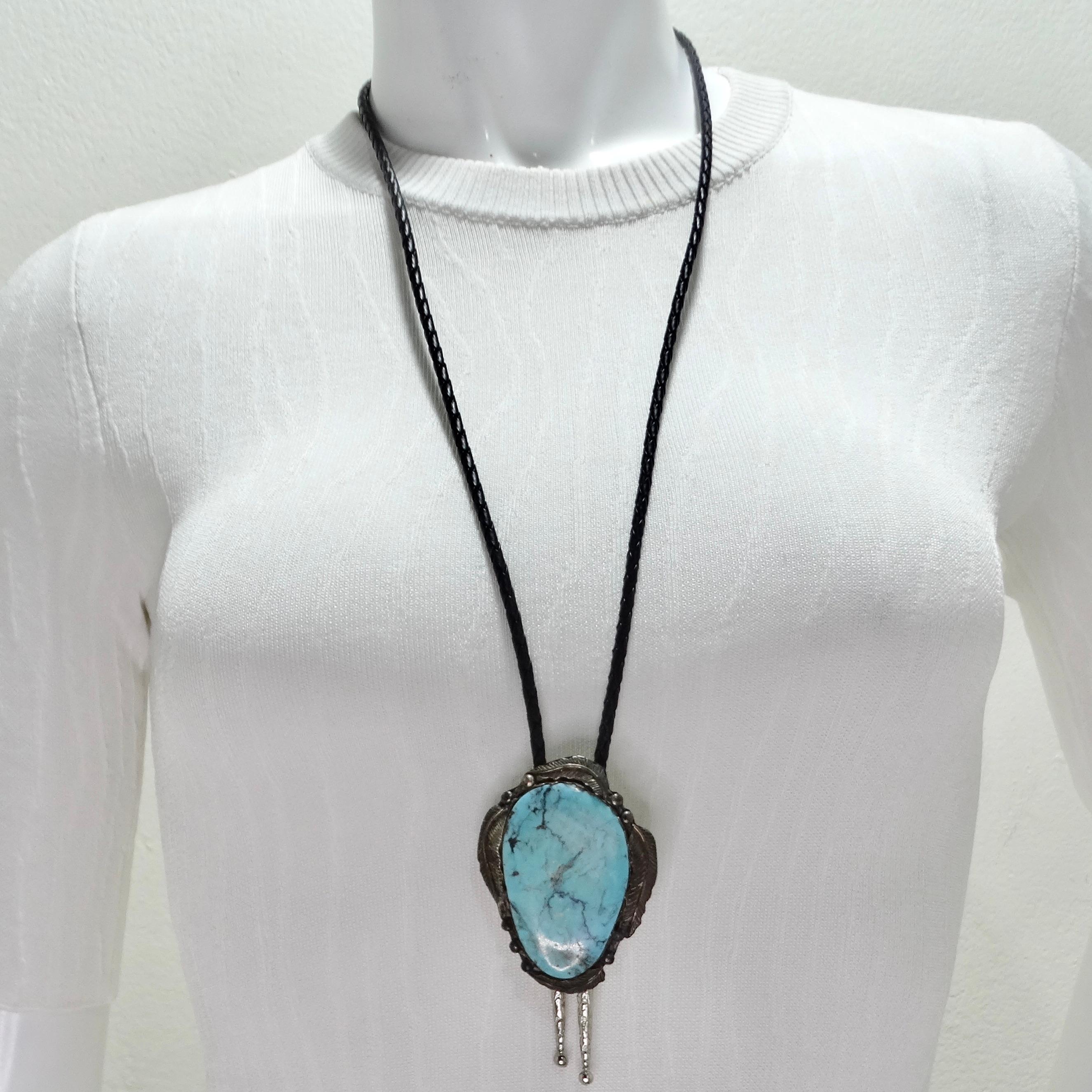 Experience the charm and craftsmanship of the 1960s with this Native American Silver Turquoise Bolo Necklace. This stunning bolo-style necklace features a black chord that highlights a vibrant round turquoise stone set in pure silver. The striking